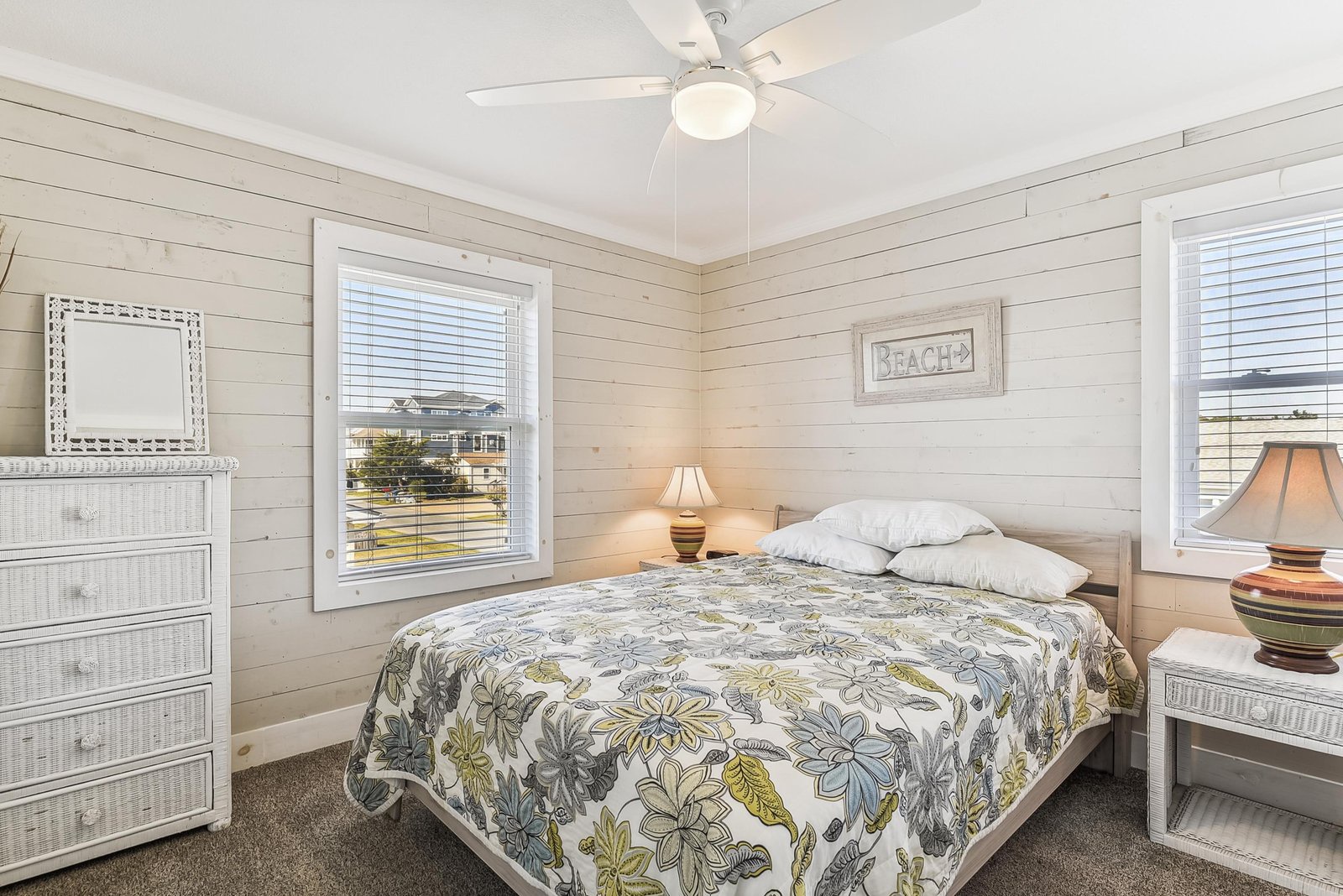 Rest easy in this peaceful beach-themed bedroom, where coastal whites and soft natural light invite your most restful nights. Ceiling fan overhead keeps you cool and comfortable.
