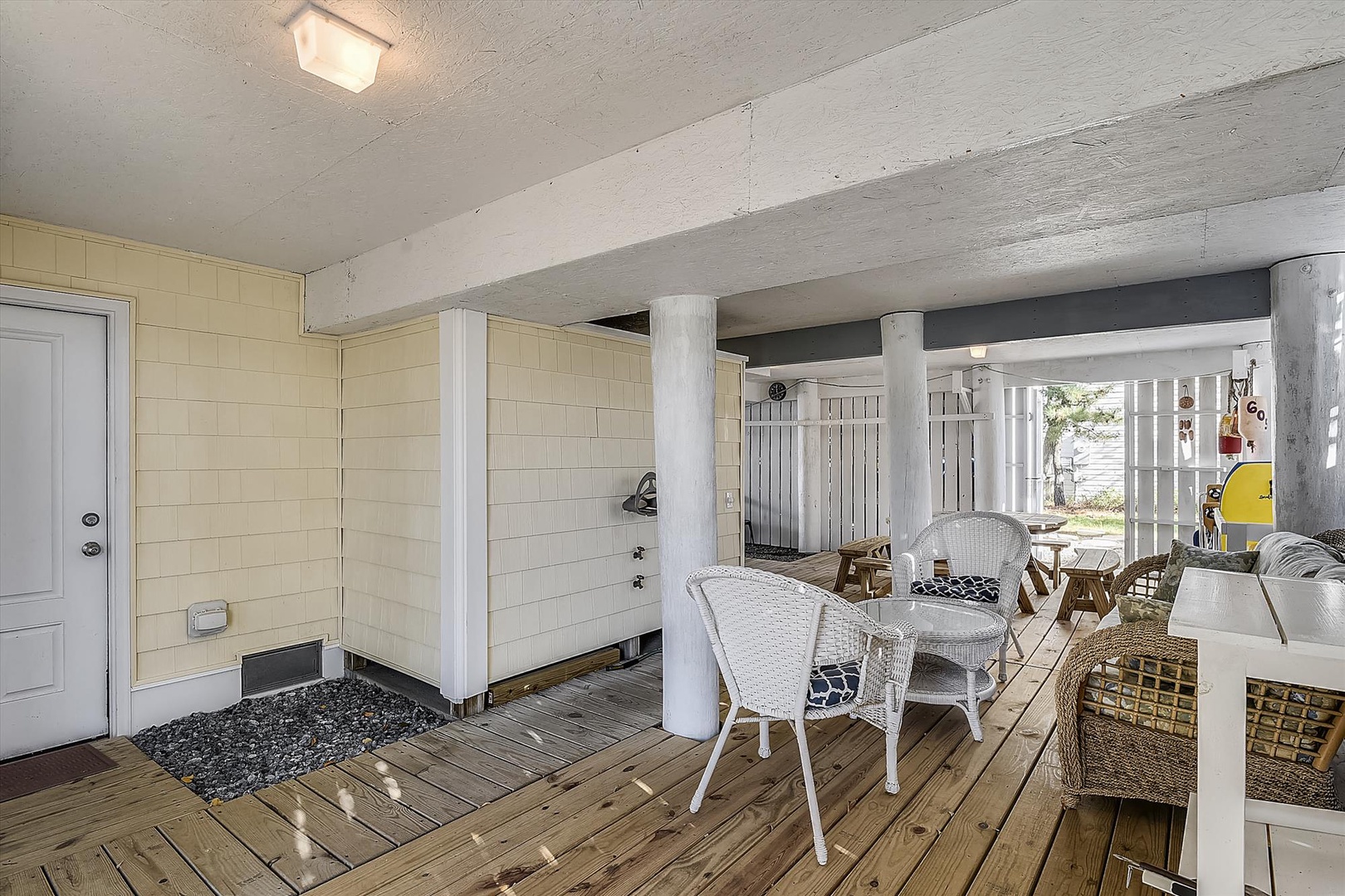 A covered outdoor patio where you can dine al fresco, relax in wicker seating, and catch glimpses of waterfront views through white picket railings—perfect for breezy mornings and sunset evenings.