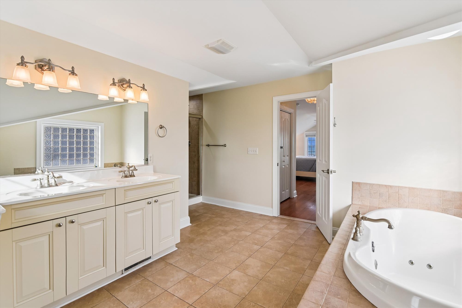 A spacious primary bathroom featuring dual vanities and a large jetted tub awaits your relaxation. Warm lighting and elegant fixtures create a soothing retreat after your adventures.