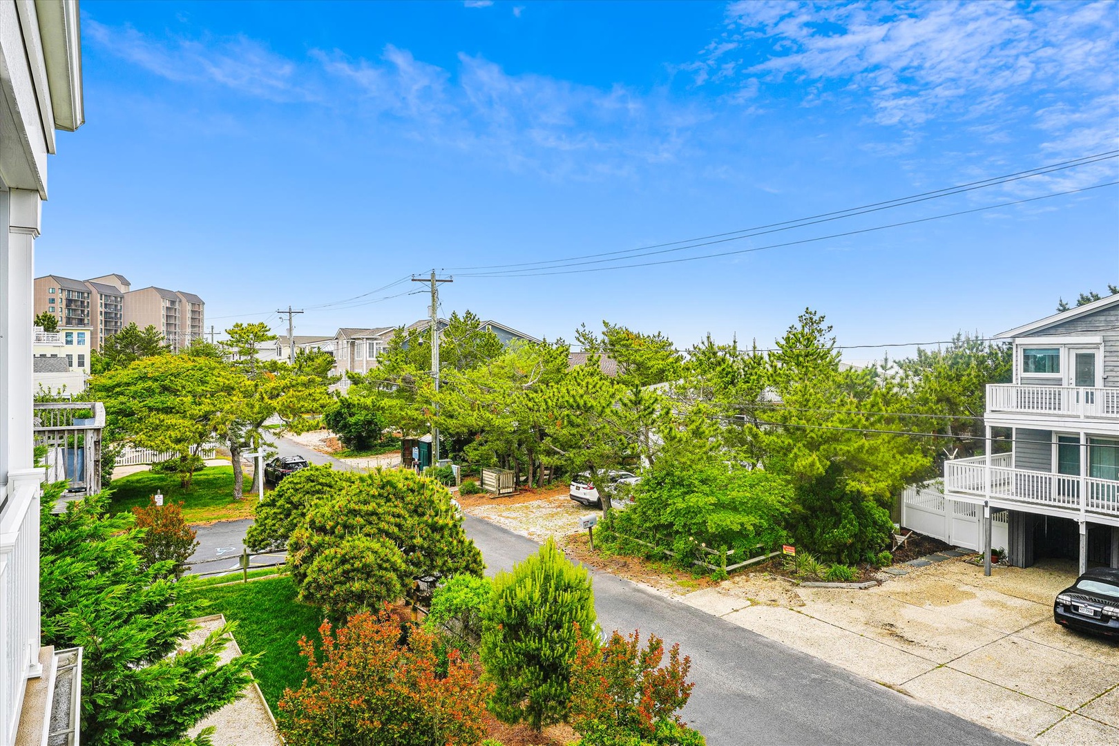 Peaceful coastal neighborhood surroundings with lush greenery and nearby residential buildings beneath clear blue skies.