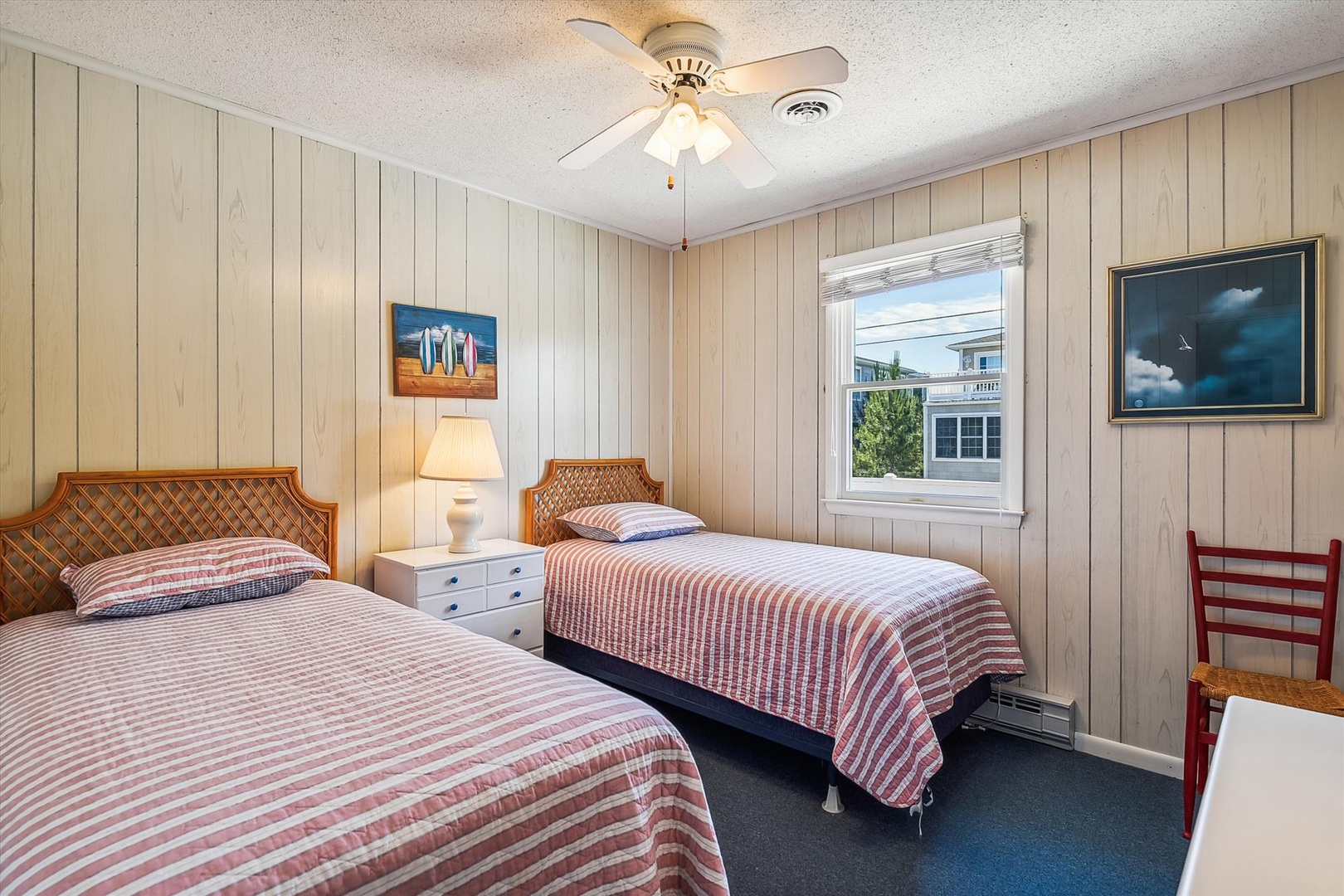 Your coastal retreat features two cozy beds with striped linens, charming whitewashed paneling, and beach-inspired artwork that brings the seaside indoors.