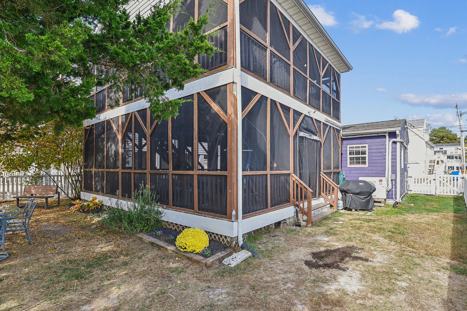 The property features a spacious screened porch with wooden framing, set among mature trees and a grassy yard—a charming residential retreat.