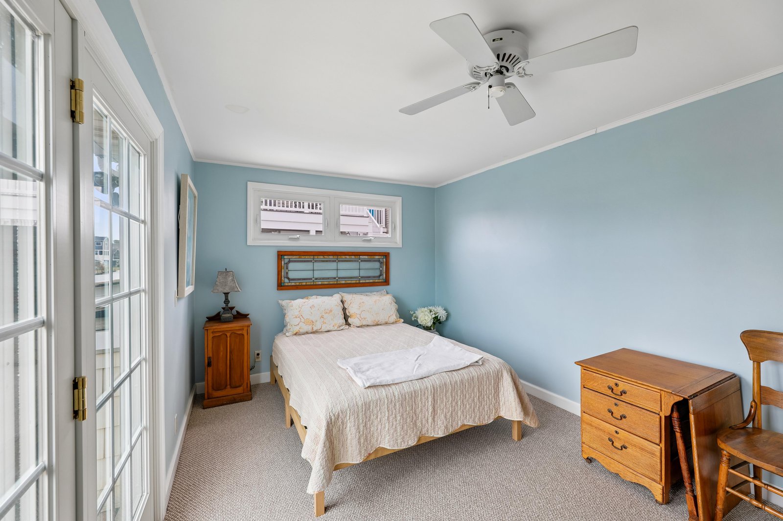 Drift into peaceful sleep in your soothing coastal-inspired bedroom, where soft blue tones and a gentle ceiling fan create a calming retreat for restful nights.