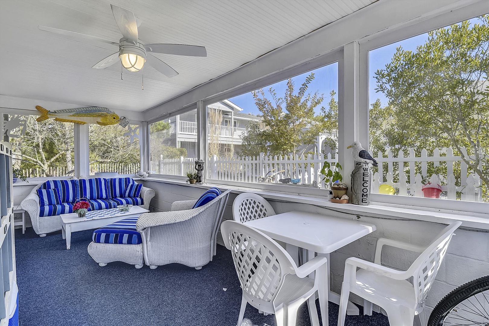 Unwind in this sun-drenched screened porch with coastal charm—your perfect spot for morning coffee or evening relaxation. Nautical-striped seating invites you to sink in, while breezy windows frame peaceful neighborhood views.