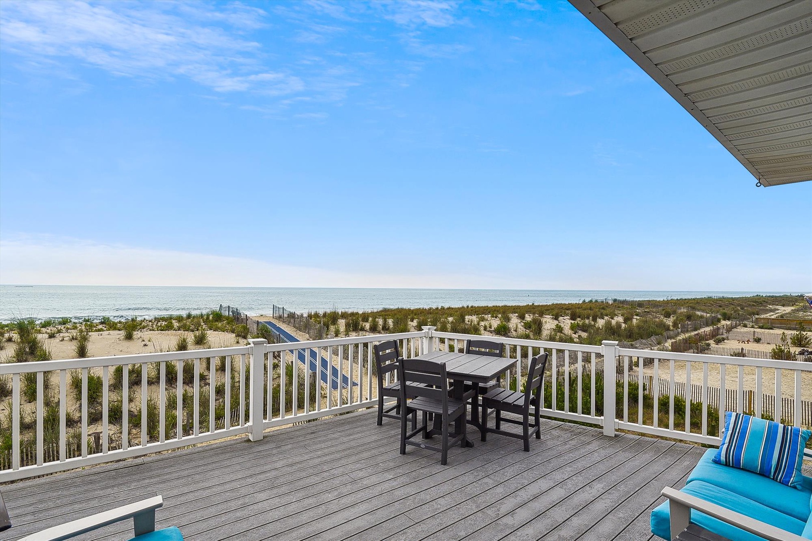 Stunning beachfront deck with direct ocean views, where your morning coffee or sunset dining overlooks endless sand, dunes, and a private boardwalk to the shore.