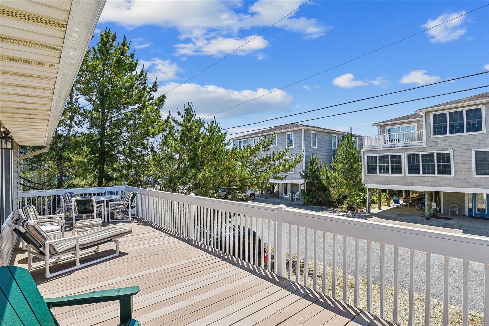 A spacious deck overlooks nearby beach homes and coastal pines, providing a peaceful spot to enjoy morning coffee or afternoon relaxation in the fresh sea breeze.
