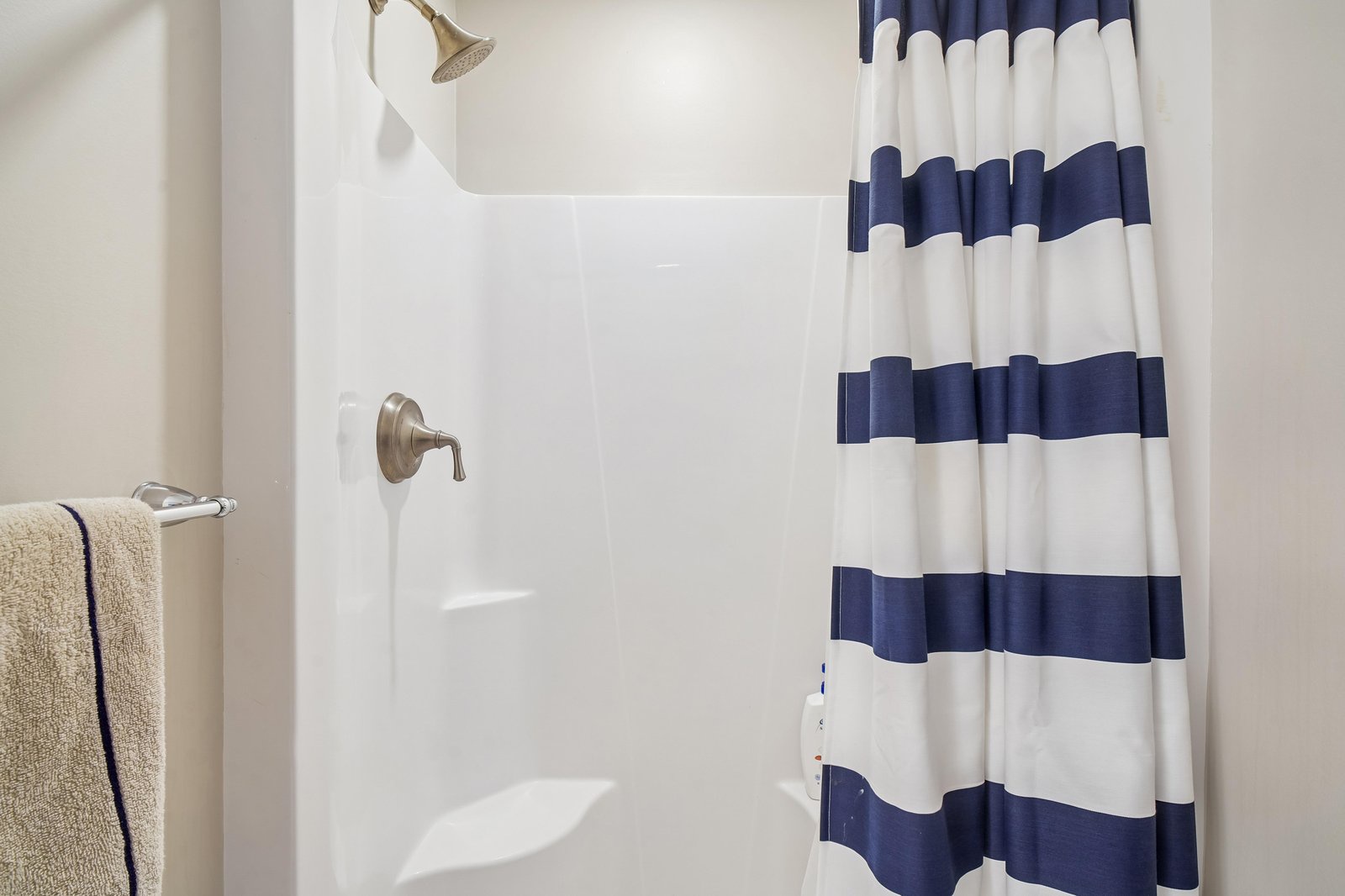 Your private bathroom offers a clean, bright shower with nautical-striped curtains and soft towels waiting for you.