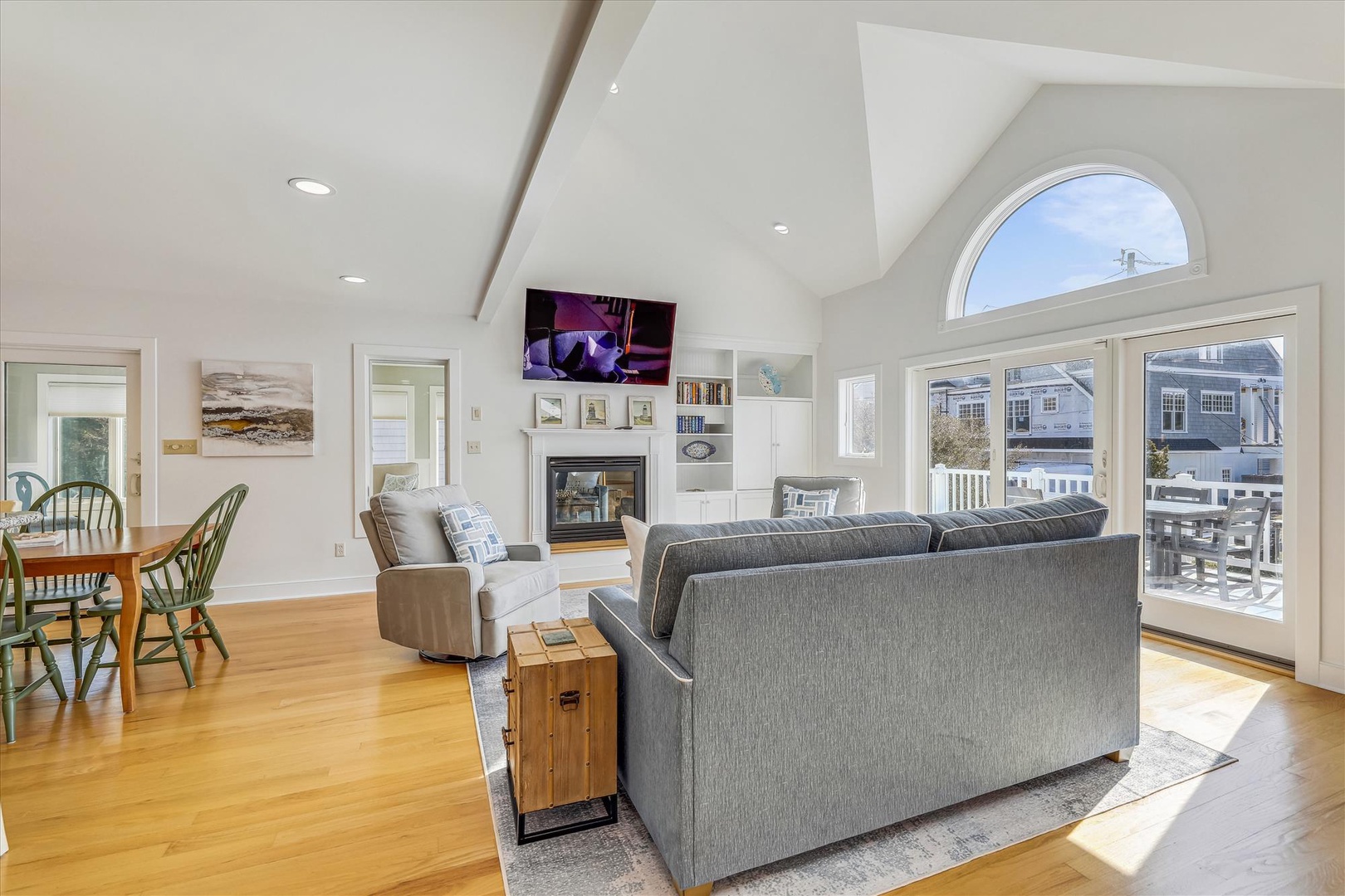 Picture yourself relaxing in this bright, airy living space with soaring vaulted ceilings and warm hardwood floors. Sunlight pours through elegant arched windows, creating a welcoming retreat.