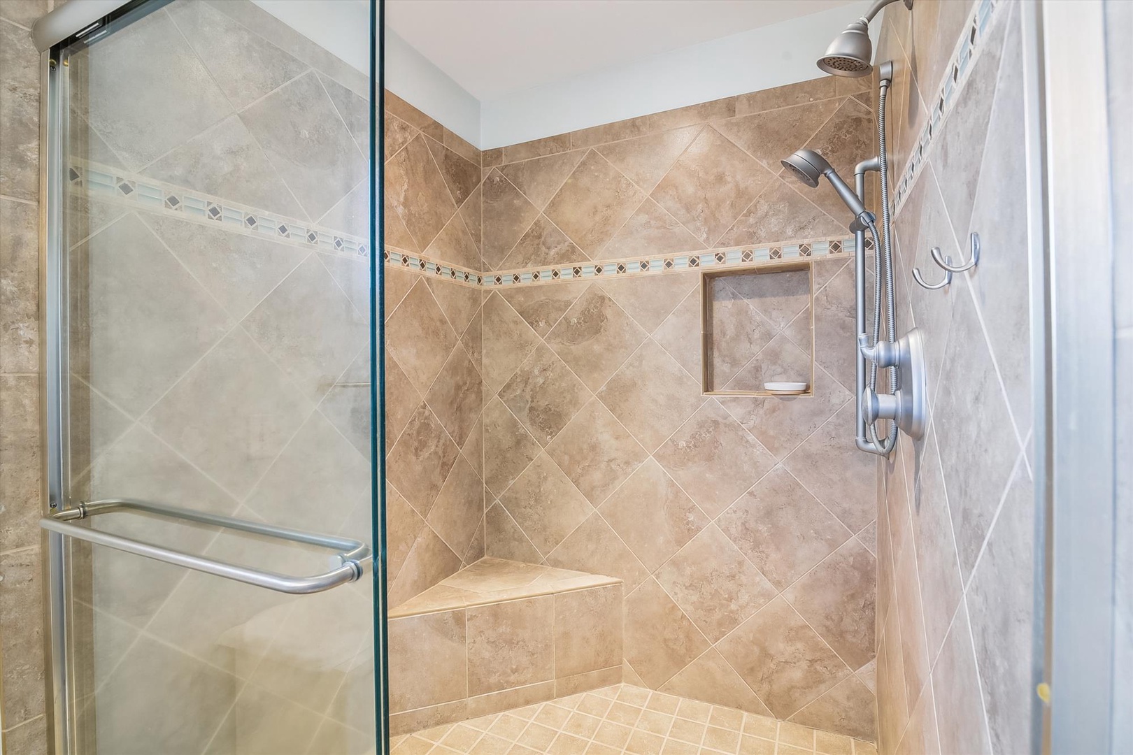 Step into your private spa-like shower with elegant travertine walls and rainfall showerhead for ultimate relaxation.