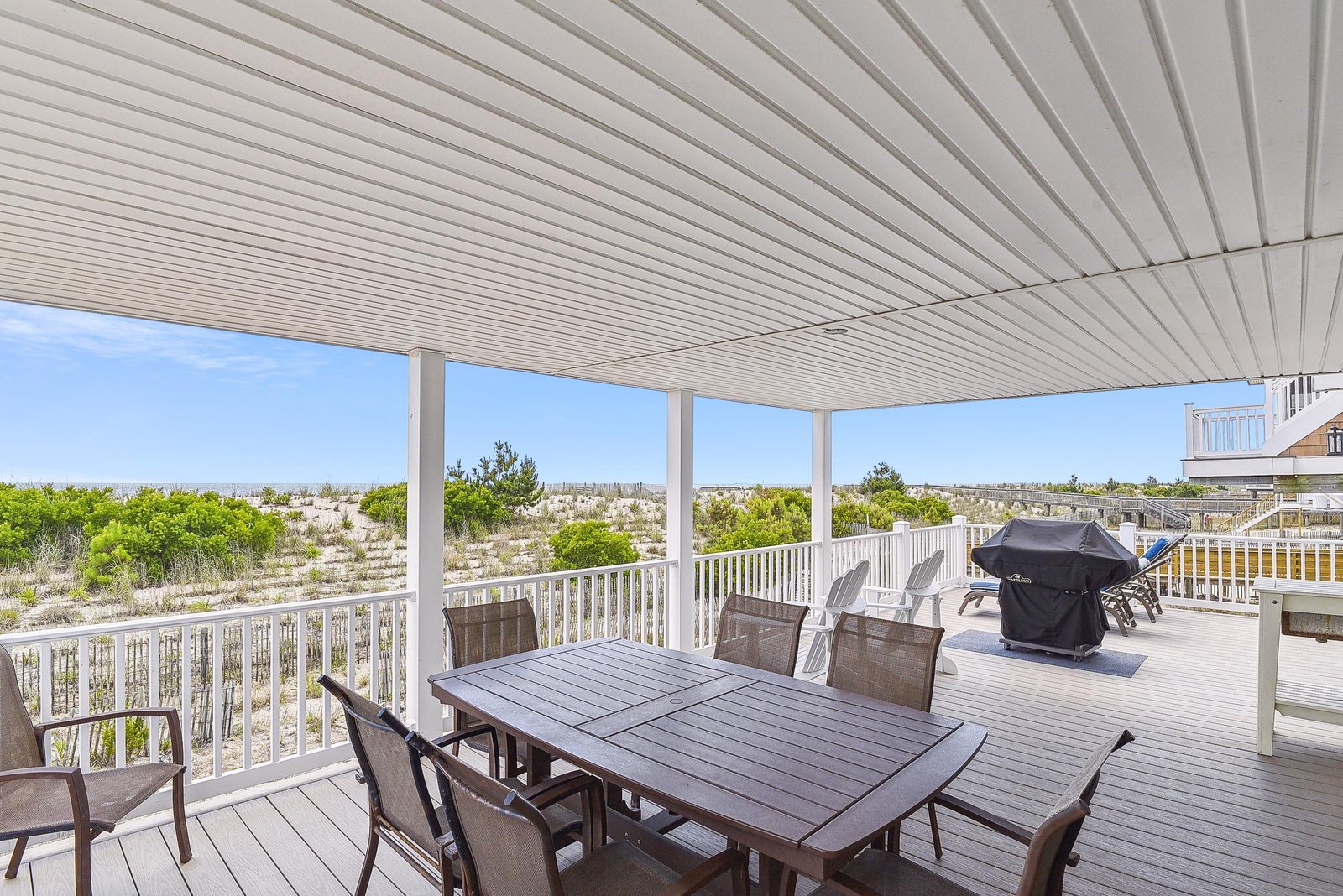 Enjoy morning coffee or sunset dinners at your private covered deck, with sweeping views of coastal dunes and greenery stretching to the horizon.