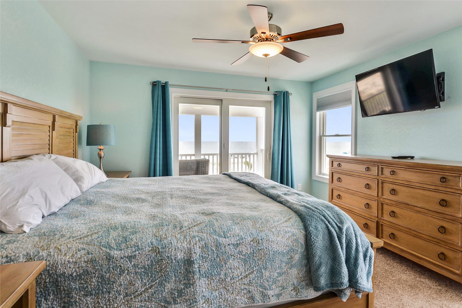 You'll drift off to sleep in this serene coastal bedroom, where soft turquoise walls and plush bedding create your peaceful retreat. Wake up to ocean views through the balcony doors.