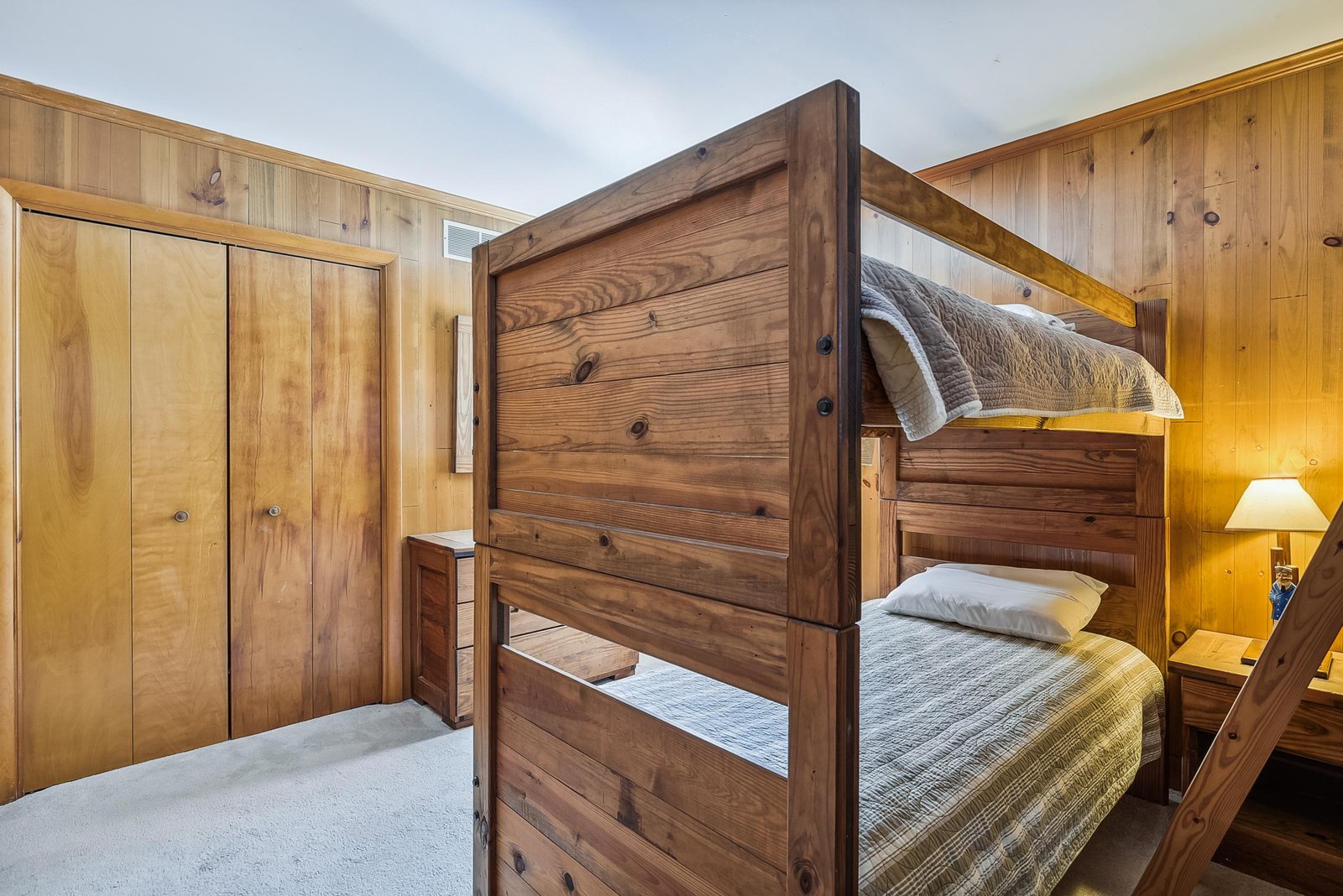 Rustic wooden bunk beds and warm knotty pine walls create a cozy mountain retreat vibe where you and your family can unwind after a day of adventure.