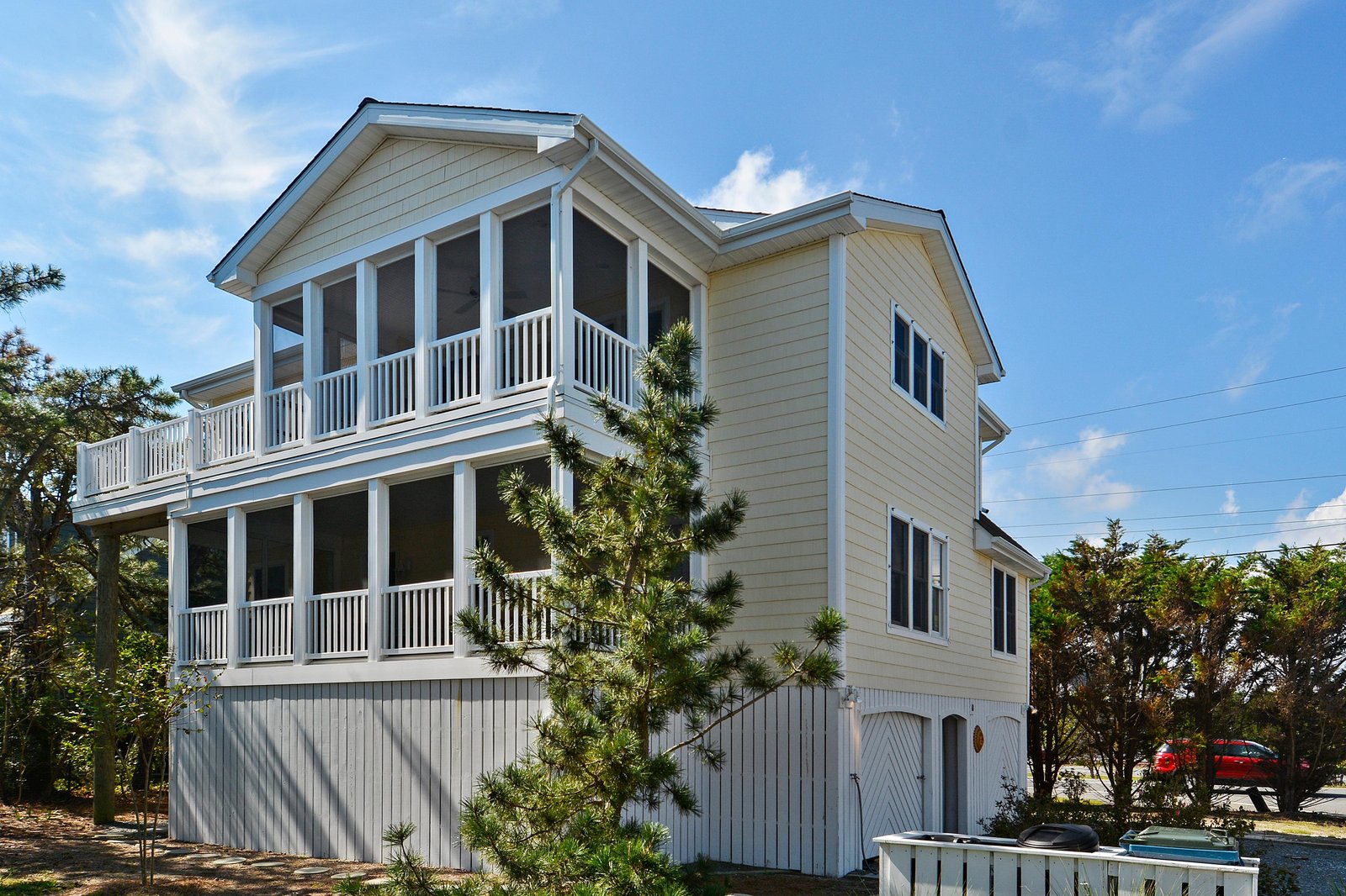 This coastal three-story home features double-decker screened porches, ground-level parking, and a bright exterior that suits the surrounding neighborhood perfectly.