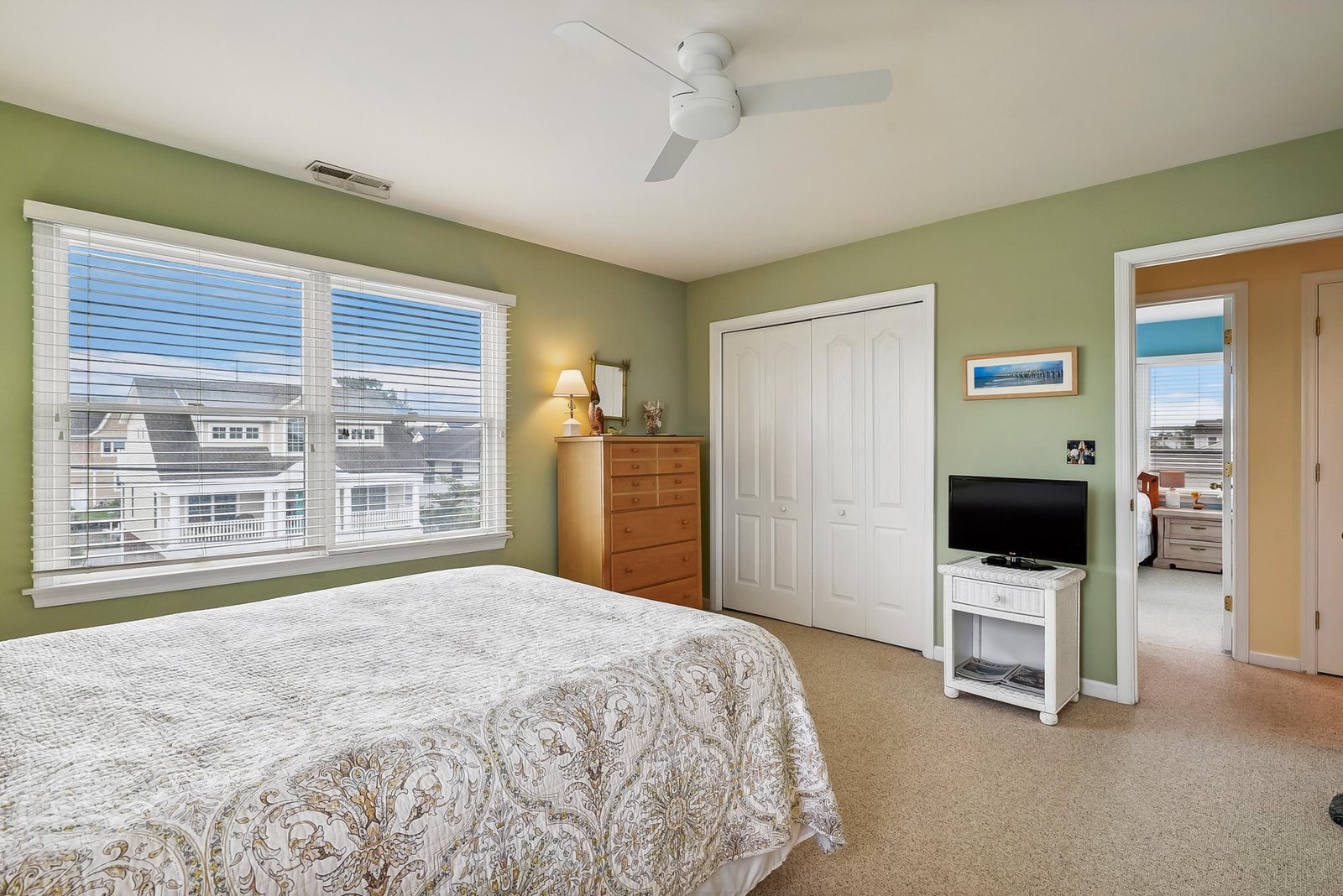 Unwind in this bright, airy bedroom with soothing green walls, a plush bed, and a ceiling fan to keep you cool. Your private space opens to an en-suite bath for easy mornings.