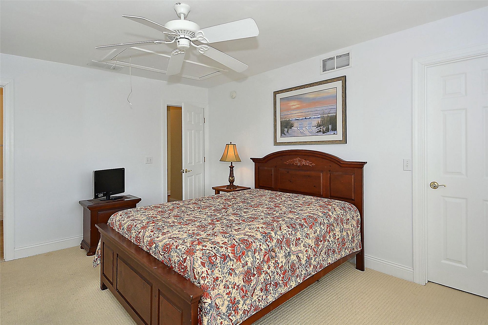 Your peaceful bedroom retreat features a plush bed, ceiling fan to keep you cool, and warm wood furnishings that invite restful nights after exploring the area.