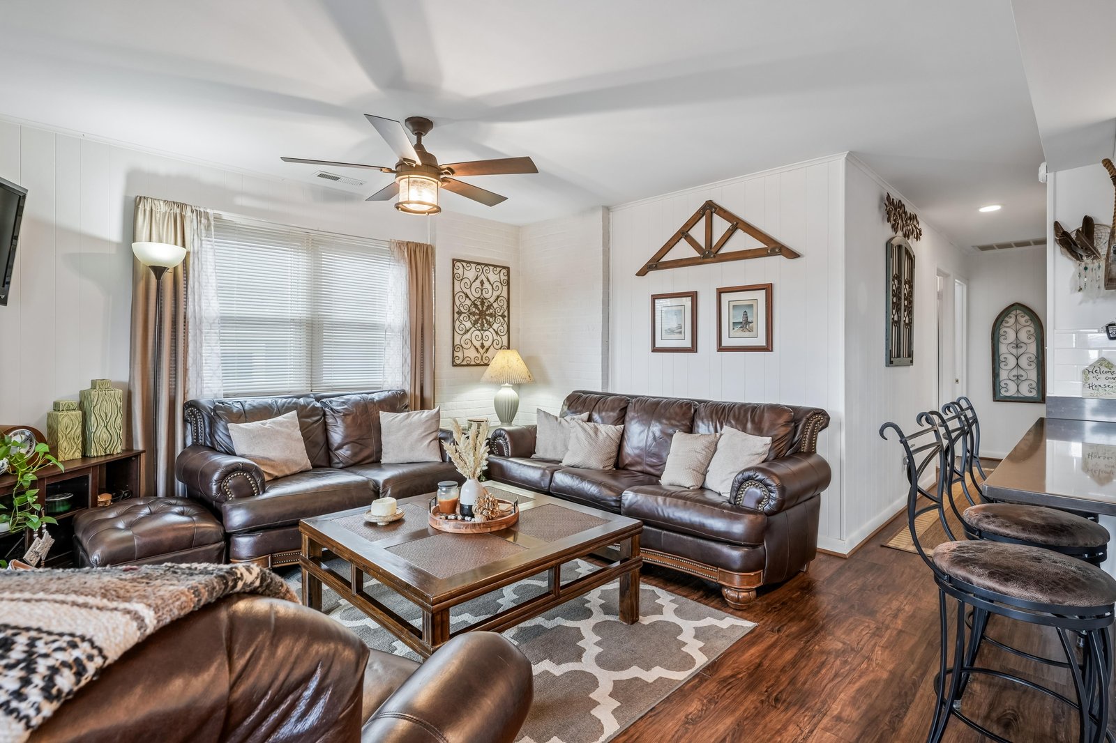 Sink into plush leather sofas in your spacious living room, where natural light and a cozy ceiling fan create the perfect spot to unwind after exploring the area.