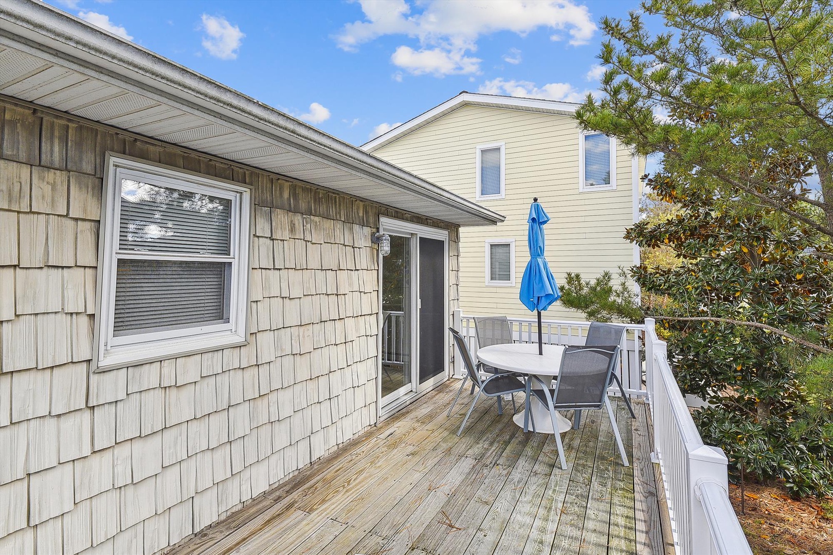 The property features a private wooden deck with outdoor dining furniture and umbrella, nestled among mature trees for peaceful seclusion.