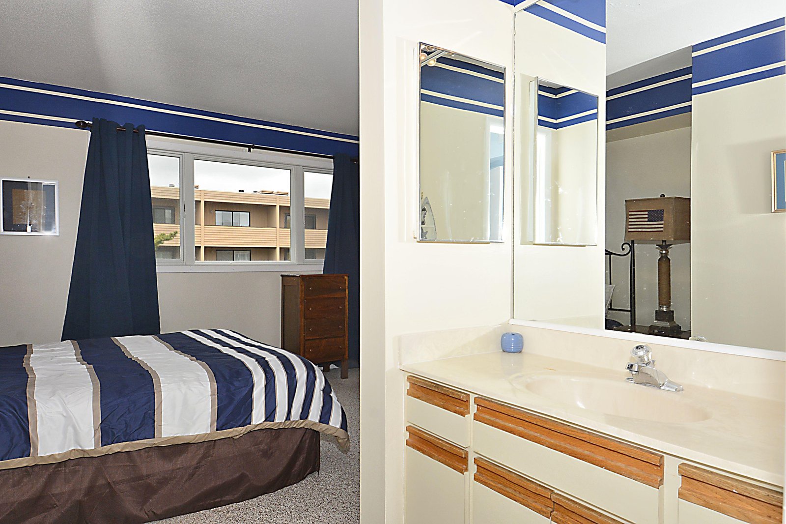 Your bedroom features crisp nautical styling with bold blue and white stripes while the adjoining bathroom offers a bright, refreshed vanity space ready for your stay.