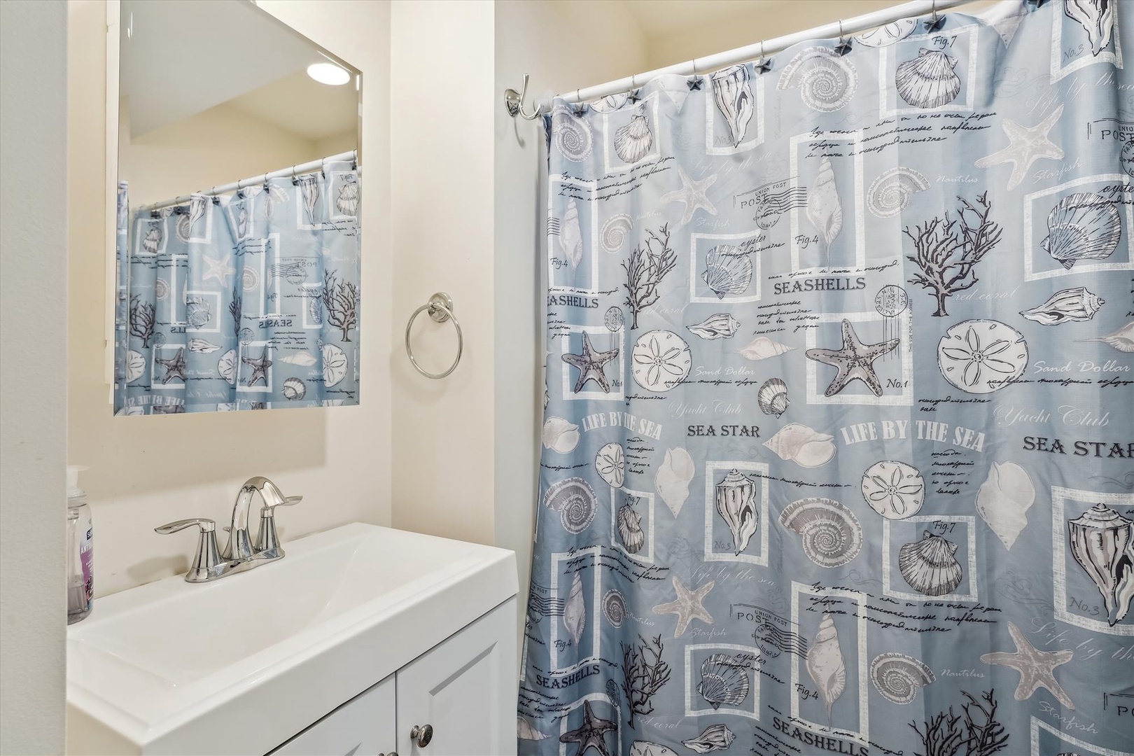 Refresh in this coastal-themed bathroom with a spacious vanity and whimsical seashell shower curtain, bringing beachy vibes to your stay.