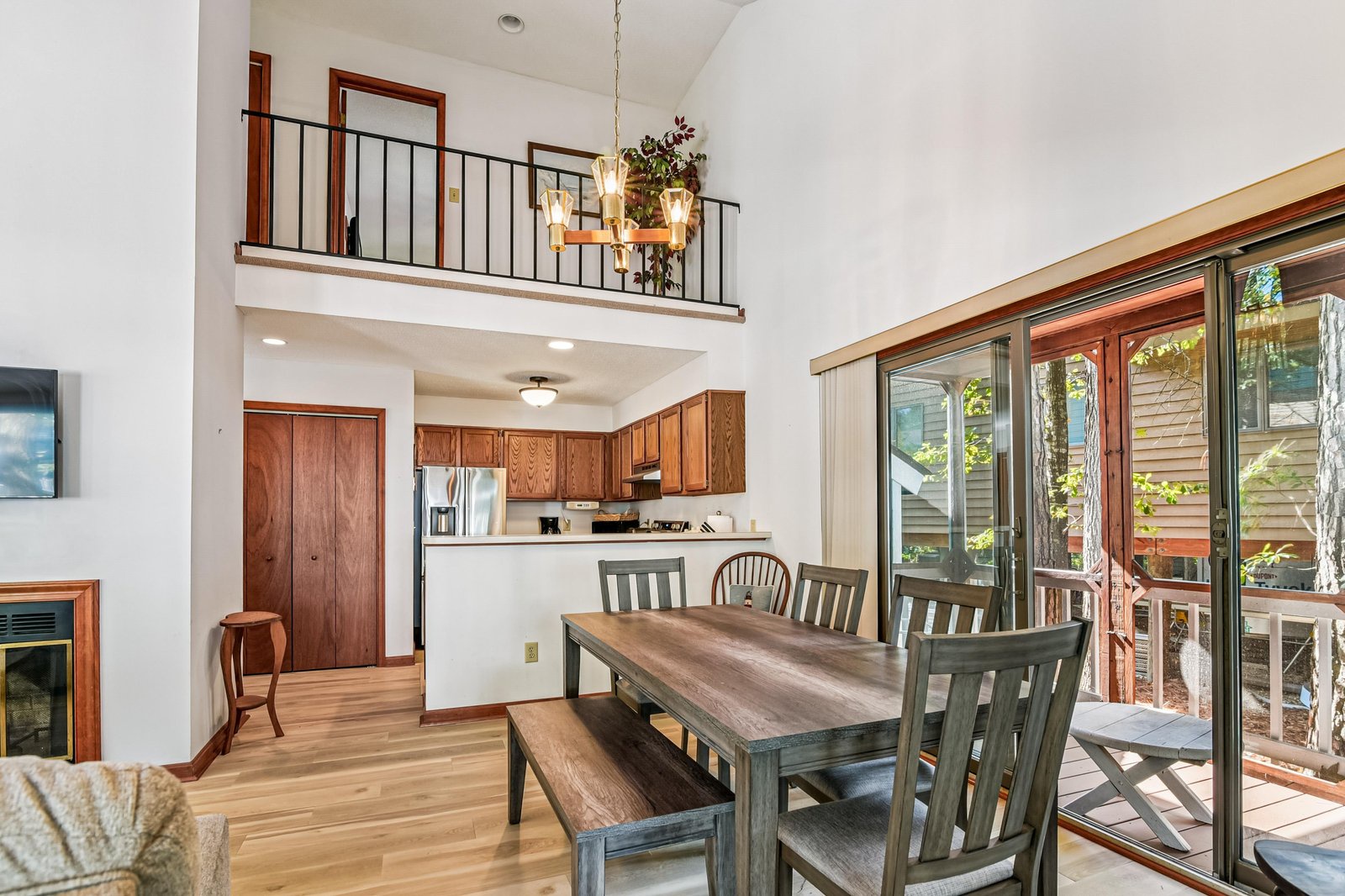 Your spacious retreat features soaring vaulted ceilings and a dramatic loft overlooking the main living area, creating an open, airy ambiance. Warm wood floors flow through to the dining area, where large glass doors frame lush forest views.