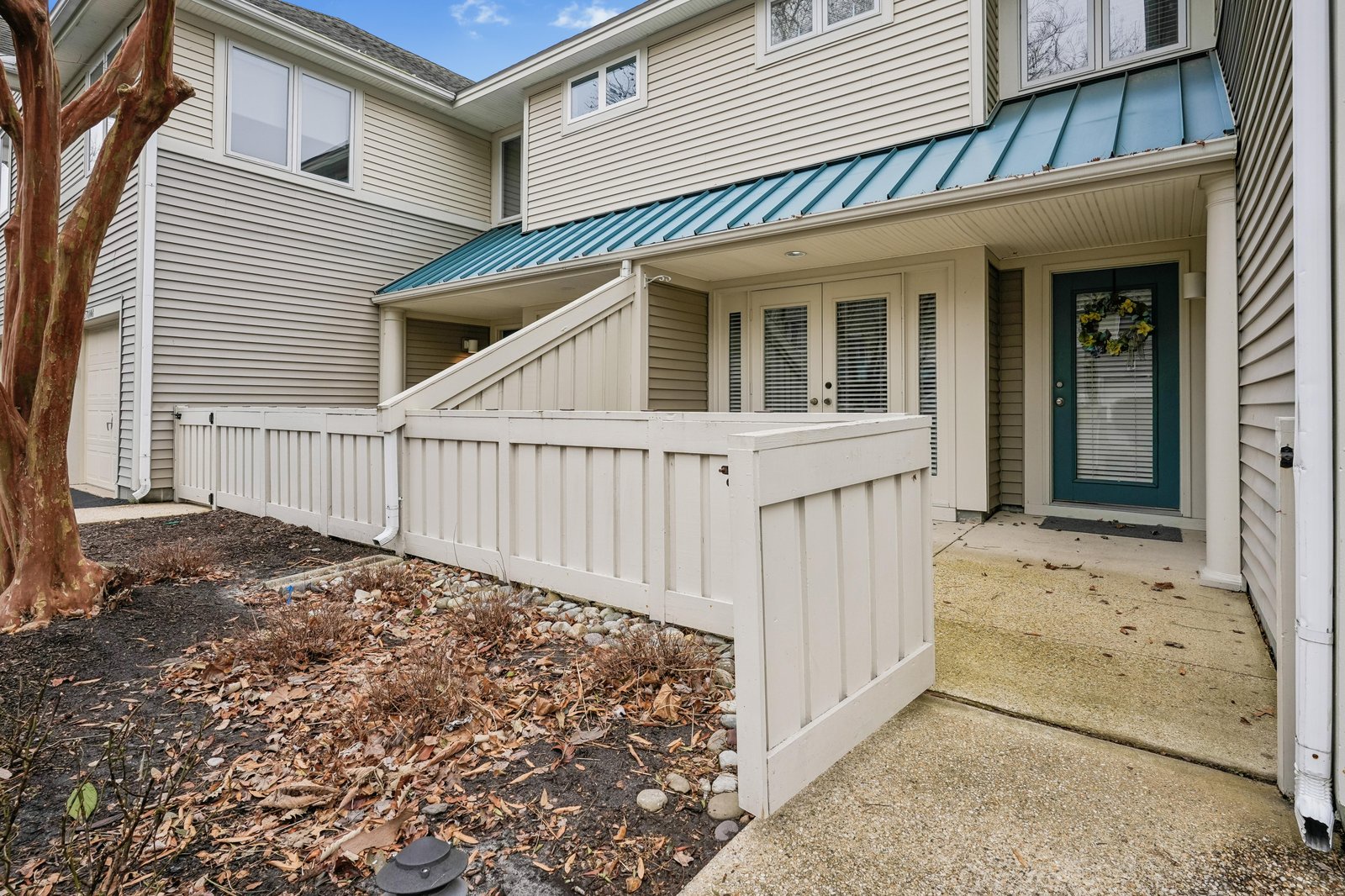 A welcoming modern home with a distinctive turquoise metal roof, accessible ramp entrance, and charming front porch—ideal for a comfortable coastal getaway.