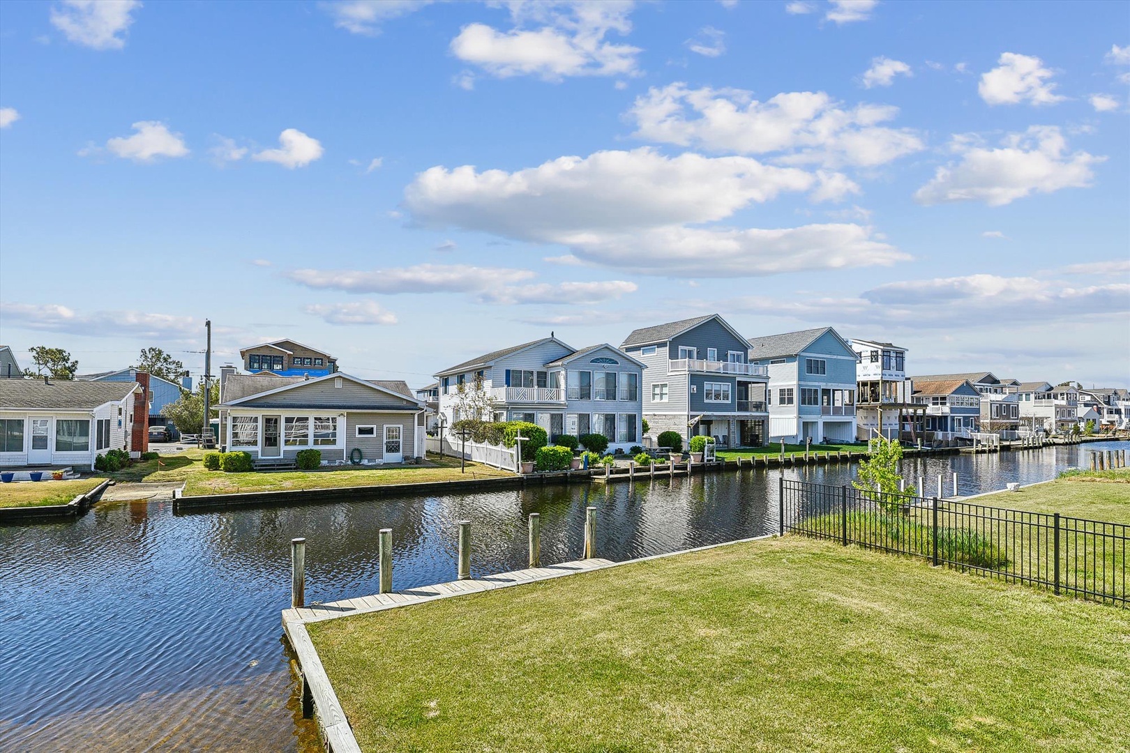 A waterfront property in a peaceful canal community with boat docks and scenic views of neighboring homes beneath a bright blue sky.