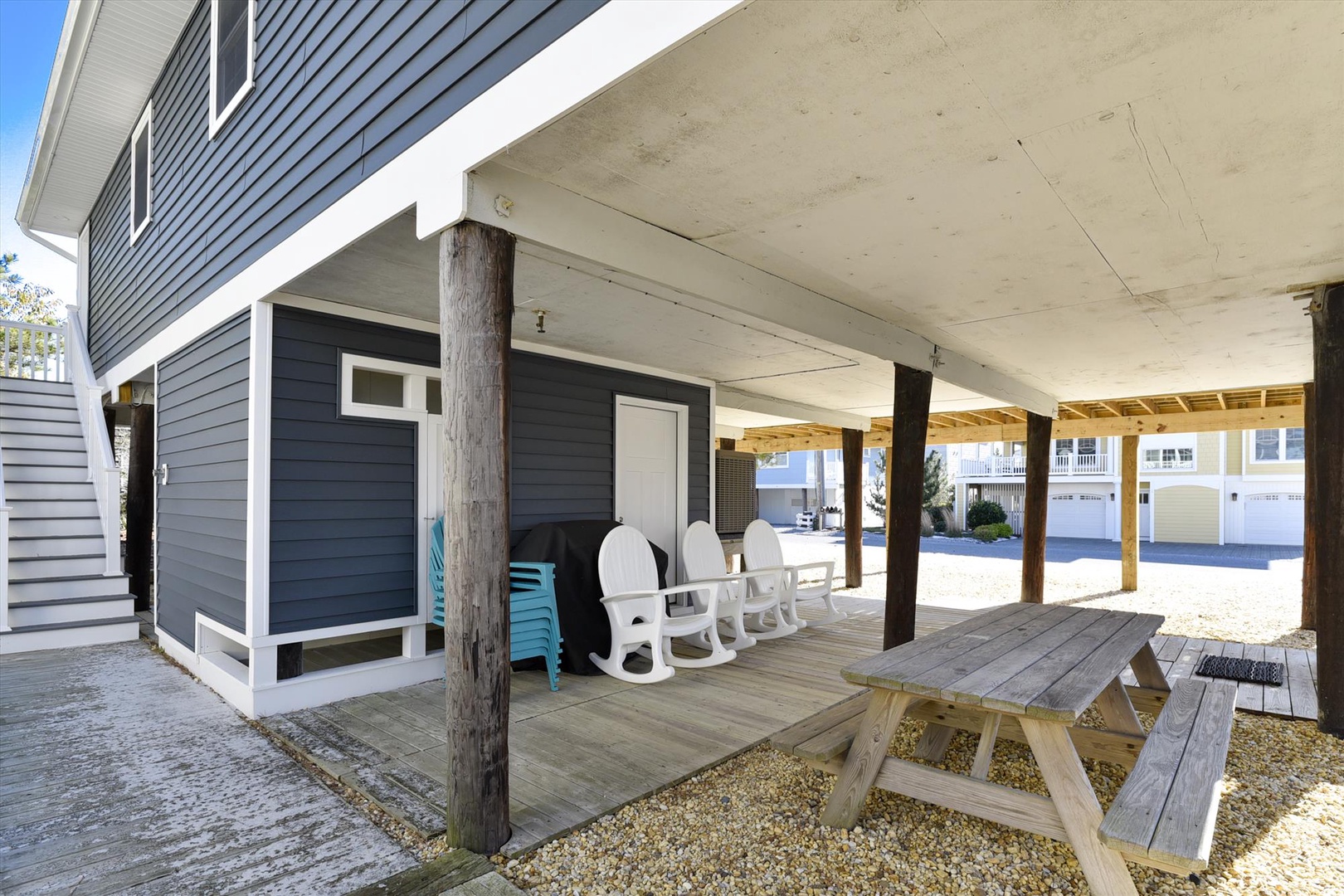 Covered outdoor area with picnic table, rocking chairs, and shaded seating—perfect for relaxing after a day at the beach.