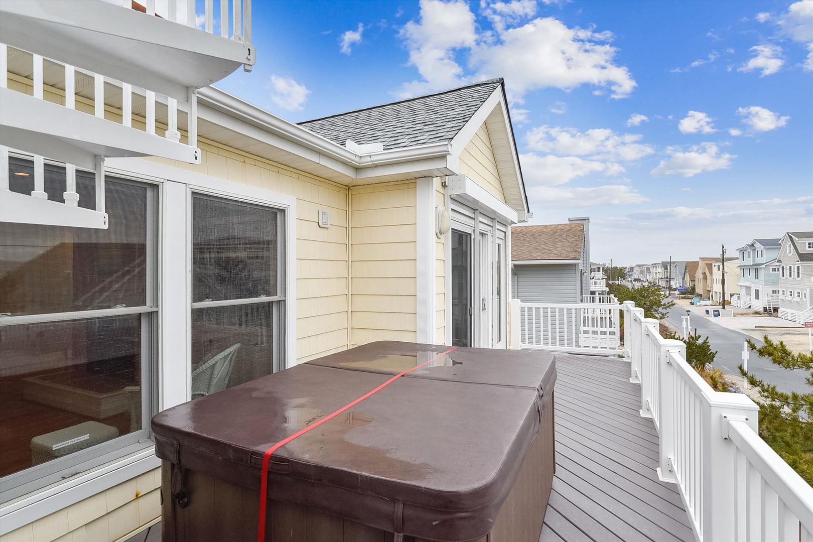 A spacious private deck offering a peaceful retreat overlooking the quiet neighborhood. The covered hot tub awaits your arrival, ready to melt away stress under the open sky.