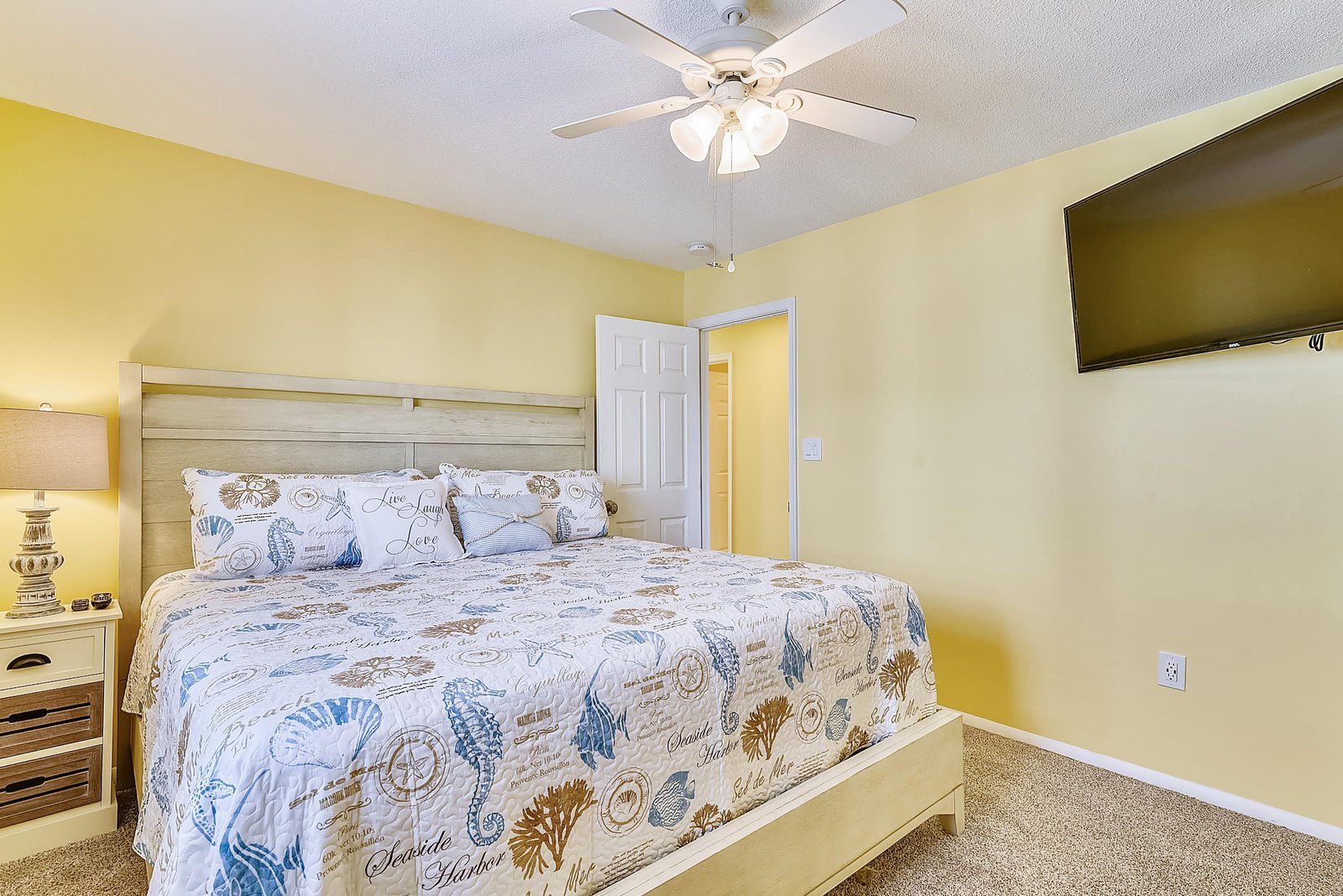 Your cheerful bedroom awaits with a comfortable bed, soft coastal linens, and a ceiling fan to keep you cool on warm evenings.