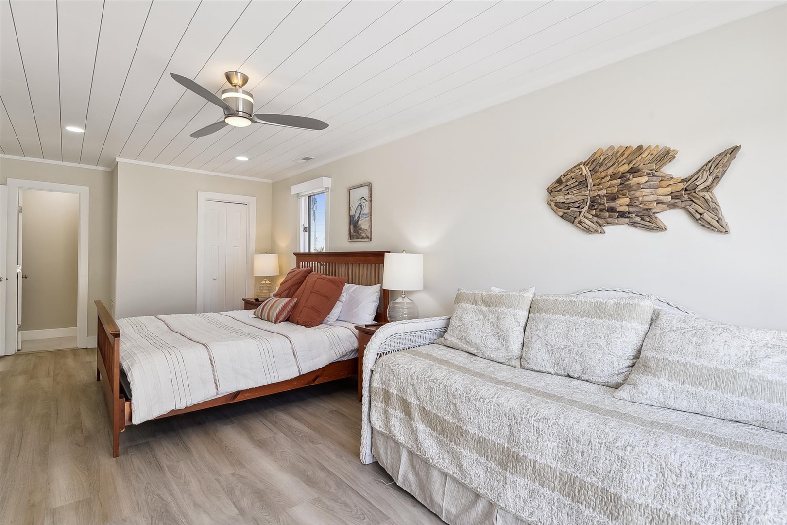 Sink into the plush sofa or cozy bed in this coastal-inspired bedroom where driftwood art and soft linens create your perfect retreat. The ceiling fan ensures comfort year-round.