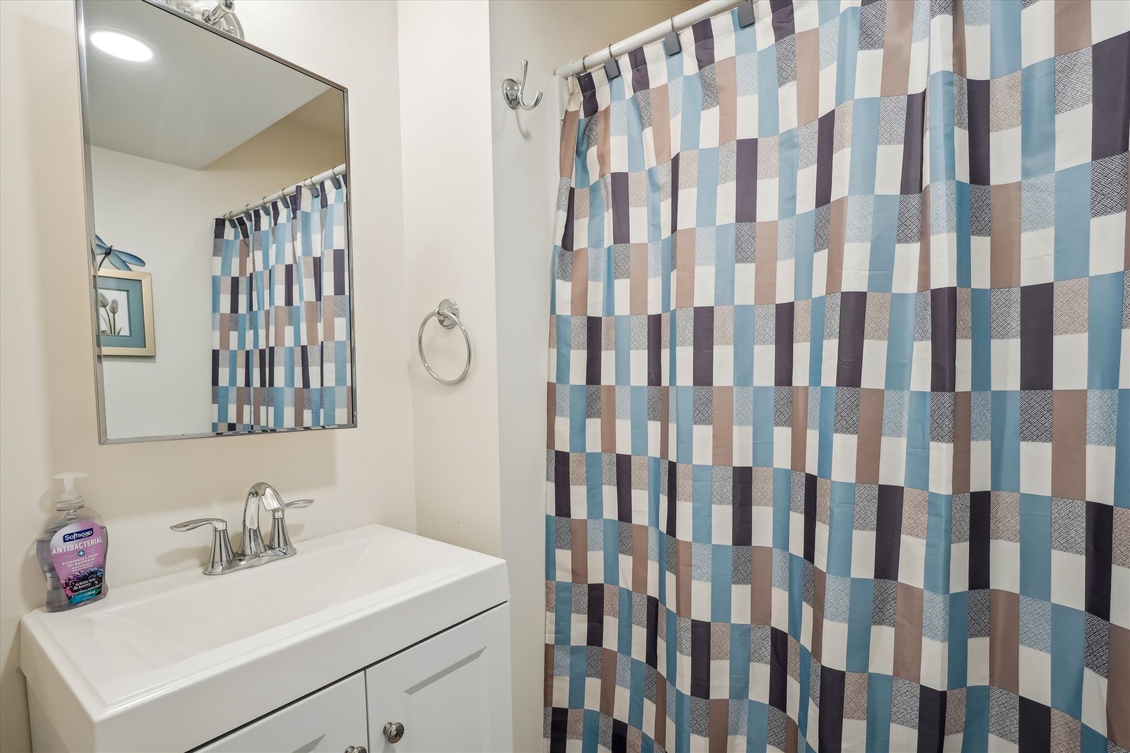 Step into your private bathroom featuring a stylish striped shower curtain, modern vanity with essential toiletries, and contemporary fixtures. Fresh linens and thoughtful touches await your arrival.