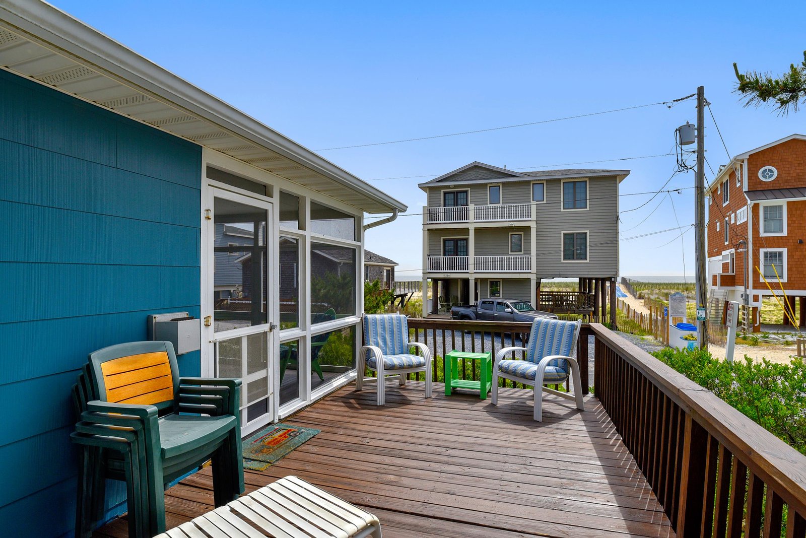 Your private deck overlooks the beach neighborhood, with colorful lounge chairs and coastal breezes inviting you to relax outdoors.
