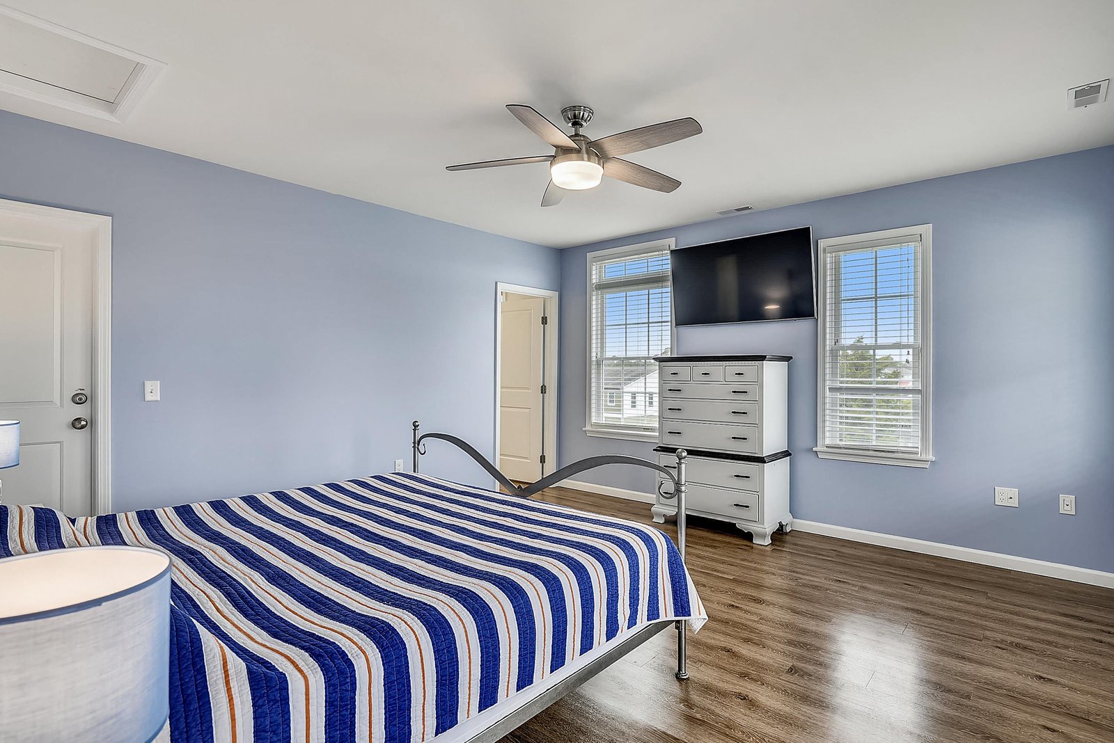 Unwind in your spacious bedroom with soothing blue walls, modern ceiling fan, and two comfortable beds perfect for restful nights after days of adventure.