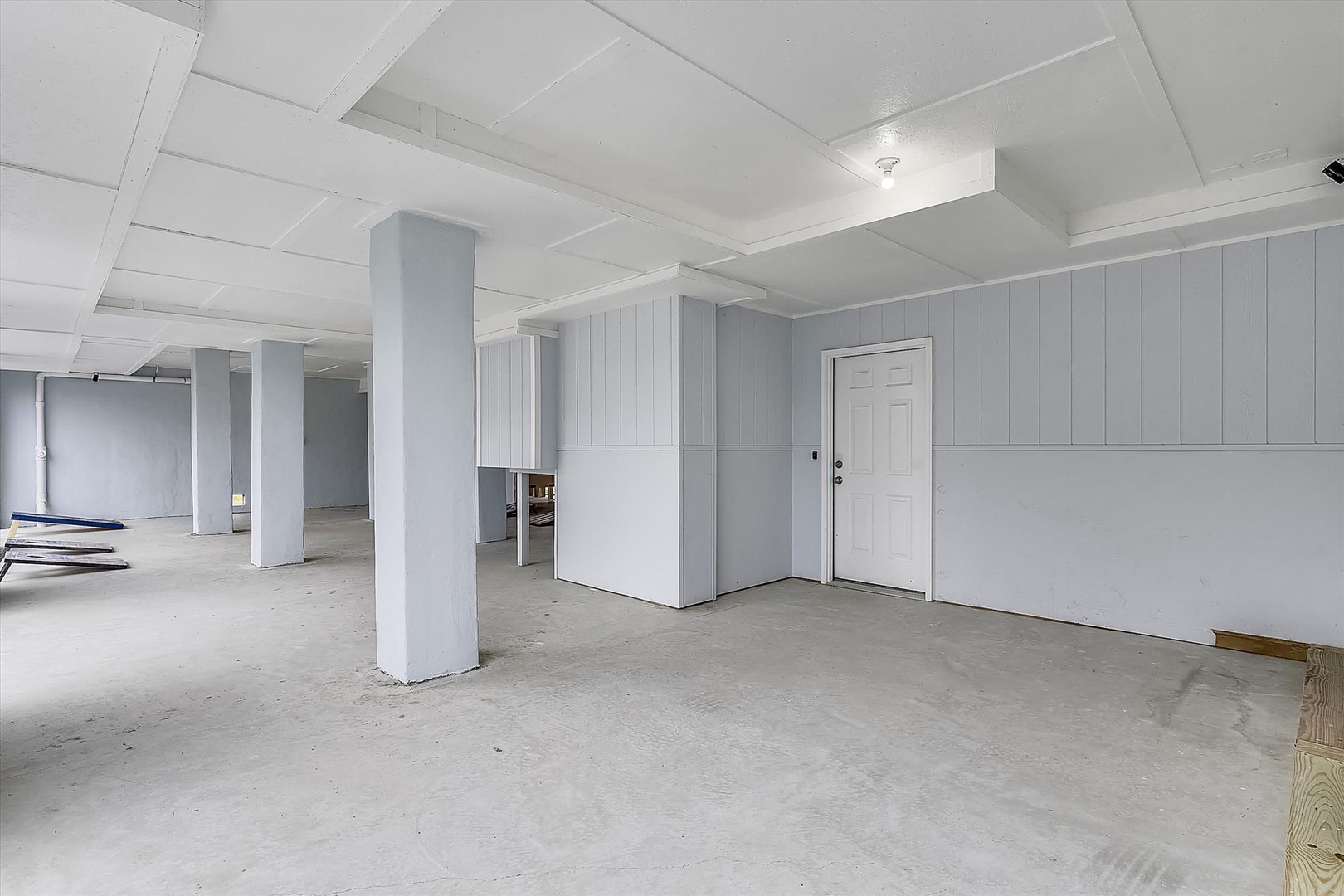 A spacious unfinished basement area with concrete floors, white-painted support columns, and practical storage potential ready for your customization ideas.