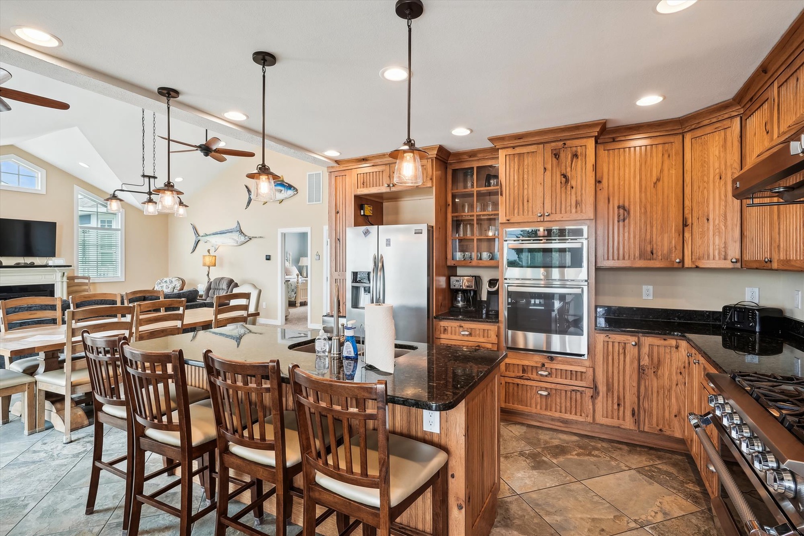 Gather around your spacious kitchen island with rich wood cabinetry and granite countertops, perfect for preparing meals and sharing stories with loved ones in this bright, open space.