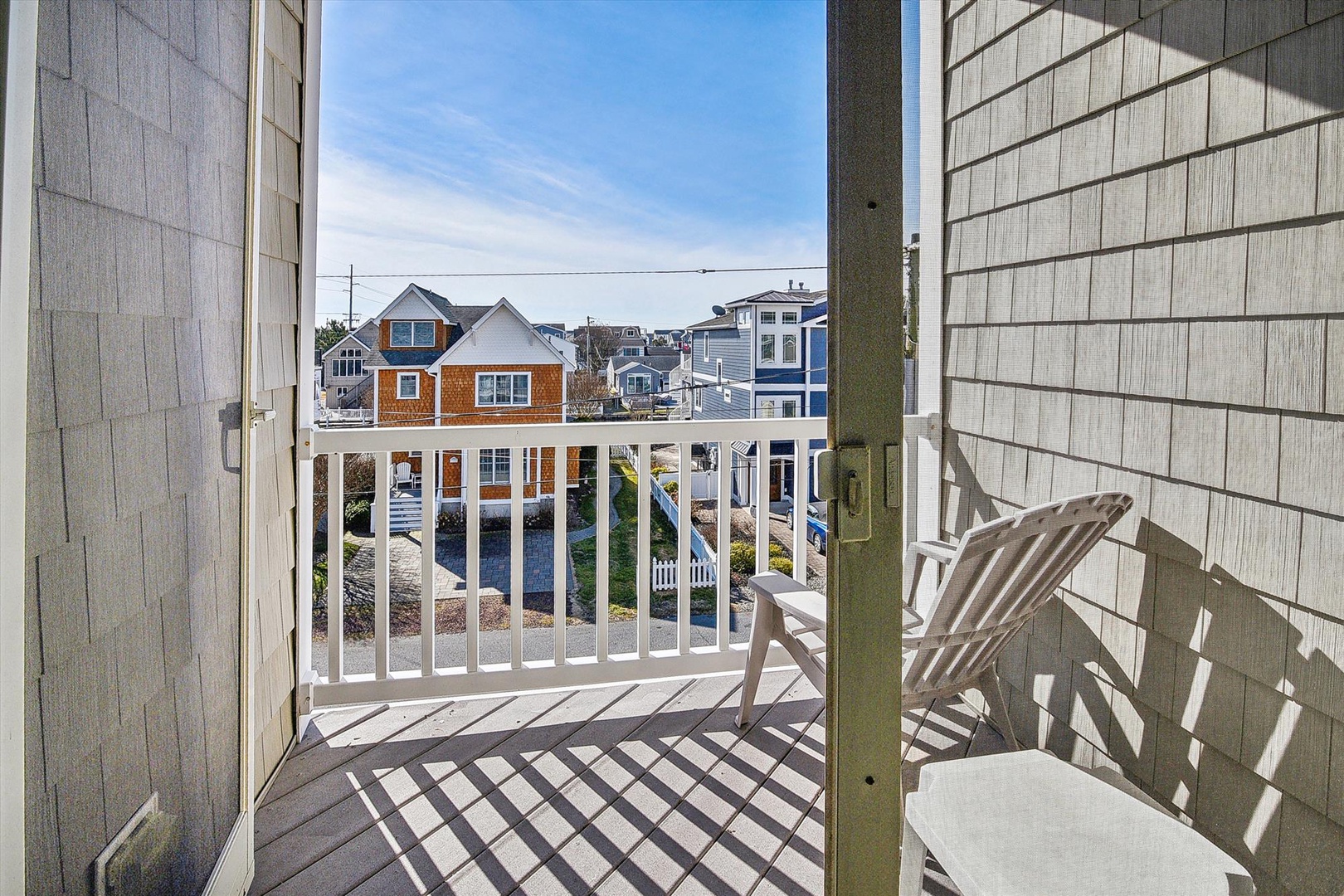 Step onto your private balcony where coastal charm meets comfort—white Adirondack chairs await your morning coffee moments.