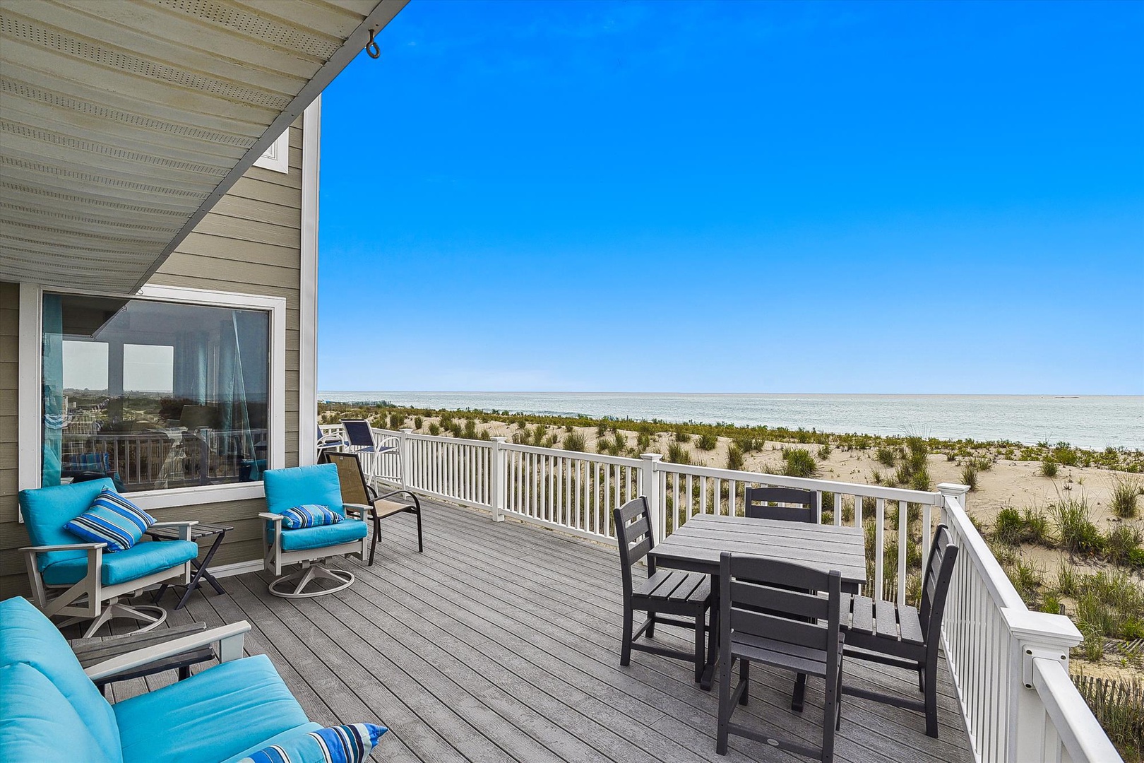 Private beachfront deck offers sweeping ocean views where you can relax on cushioned seating or dine al fresco just steps from the sand.