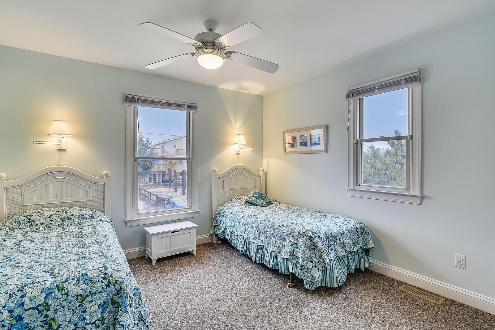 Drift off in this peaceful bedroom with twin beds dressed in calming coastal colors. Natural light fills your space through large windows, and the ceiling fan keeps you comfortable all night.