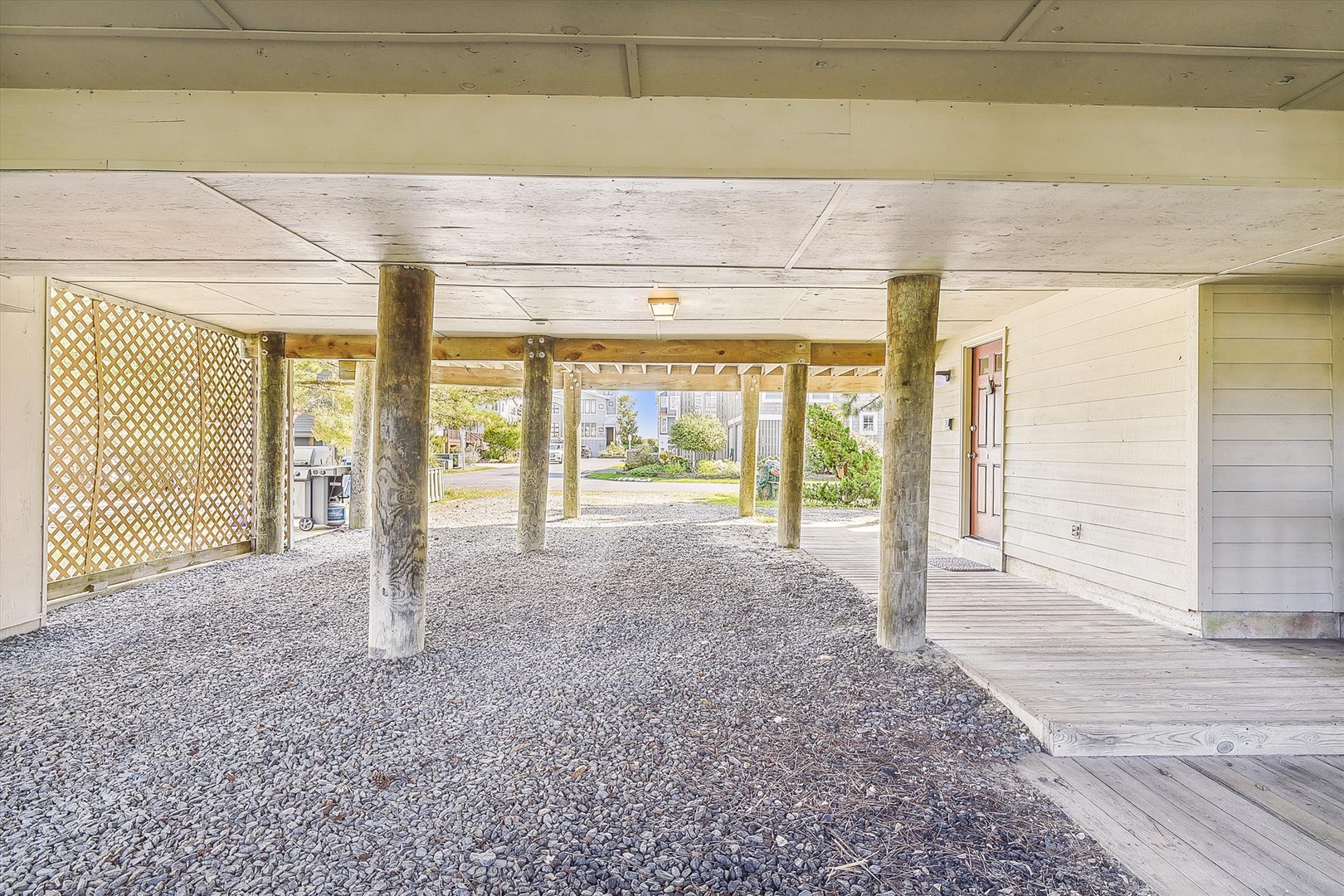 Covered parking with gravel surface provides convenient ground-level storage and protection for vehicles beneath the property.