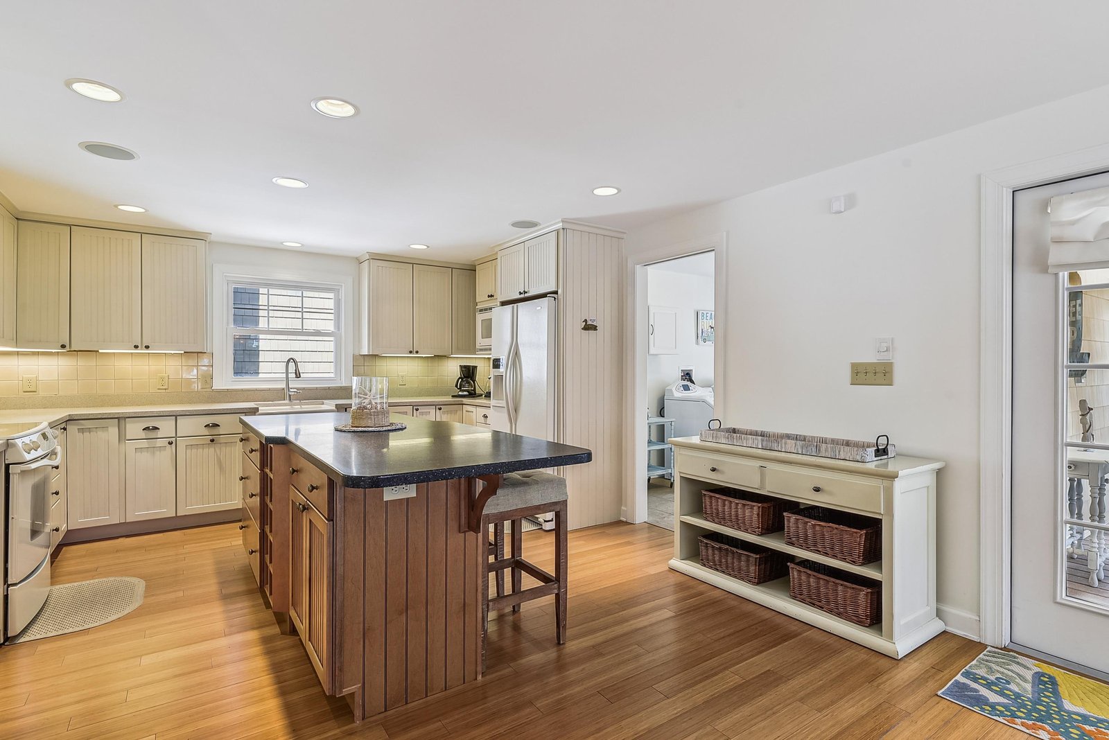 A bright and welcoming kitchen awaits, featuring warm wood floors, modern appliances, and a cozy breakfast bar where you can enjoy your morning coffee in comfort.