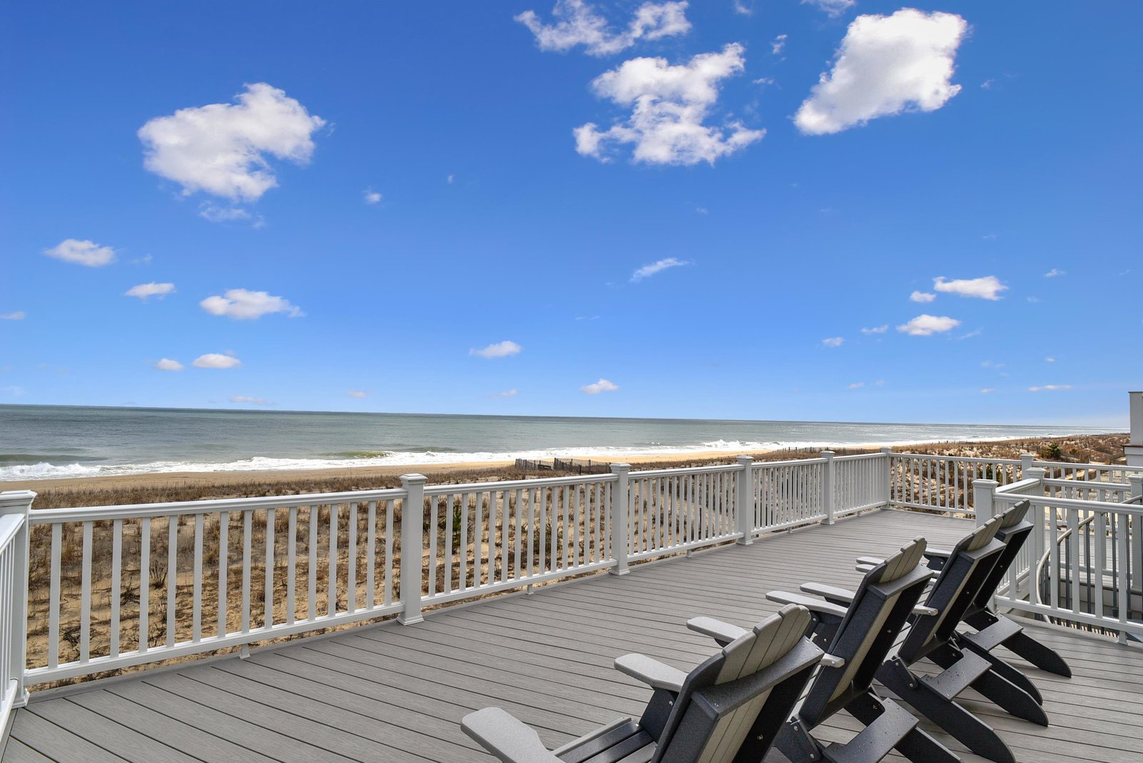 A spacious beachfront deck with comfortable Adirondack chairs offers direct access to soft sand and rolling waves, making this your perfect spot to unwind and soak up the coastal sunshine.