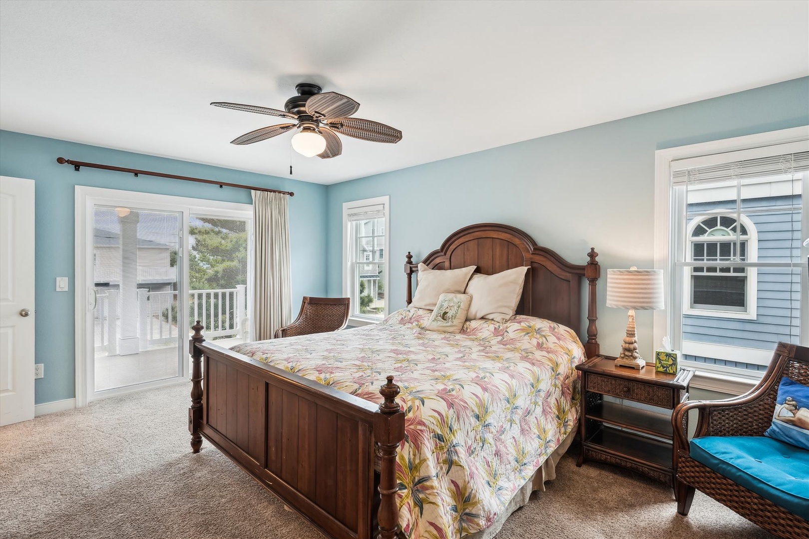Sink into plush tropical bedding under a coastal ceiling fan, with gentle ocean breezes drifting through your private balcony doors and soft daylight illuminating your serene retreat.