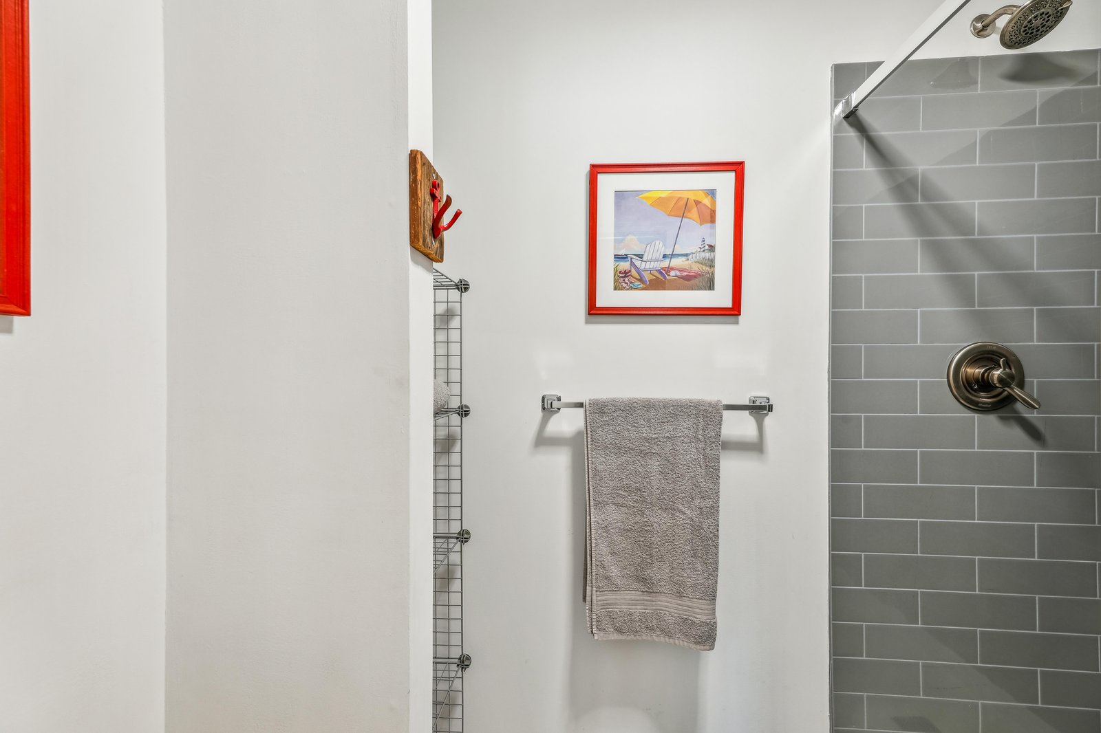 Step into your stylish bathroom featuring sleek subway tile and a refreshing rainfall showerhead. Soft towels await, and cheerful beach artwork adds a coastal touch to your daily routine.