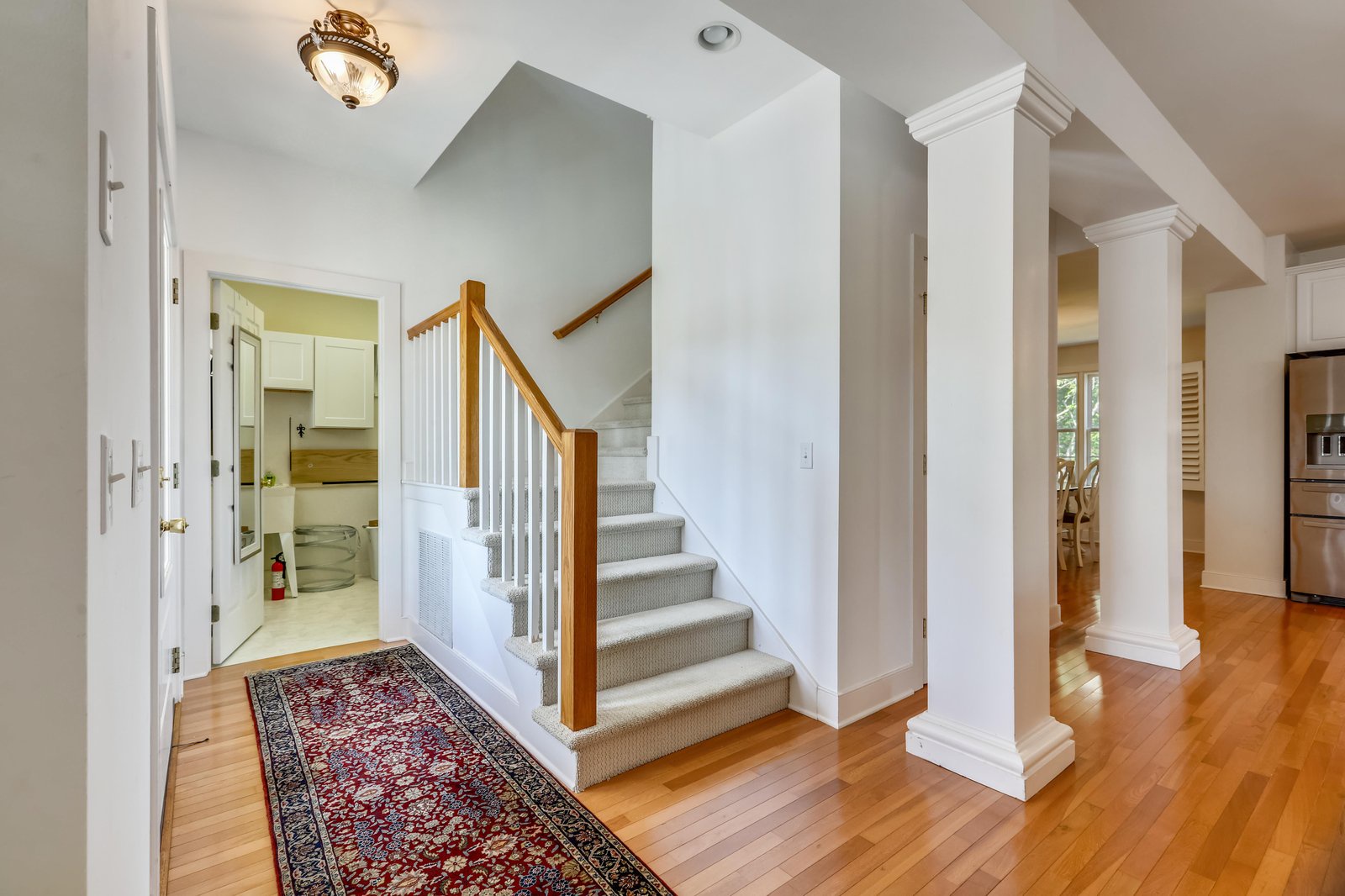 Step into a bright, welcoming entryway with gleaming hardwood floors and elegant columns that set the tone for your stay.