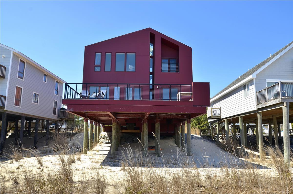 A striking modern beach house elevated on pilings sits directly on the sandy dunes, promising breathtaking coastal living just steps from the shore.