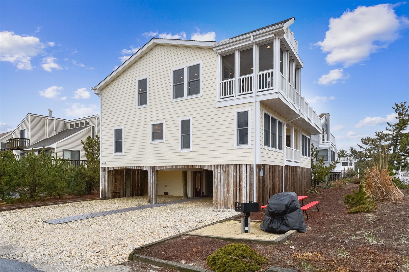 Spacious coastal rental with screened upper deck and covered parking on stilts, nestled among native greenery. Elevated design provides extra storage and outdoor gathering space.