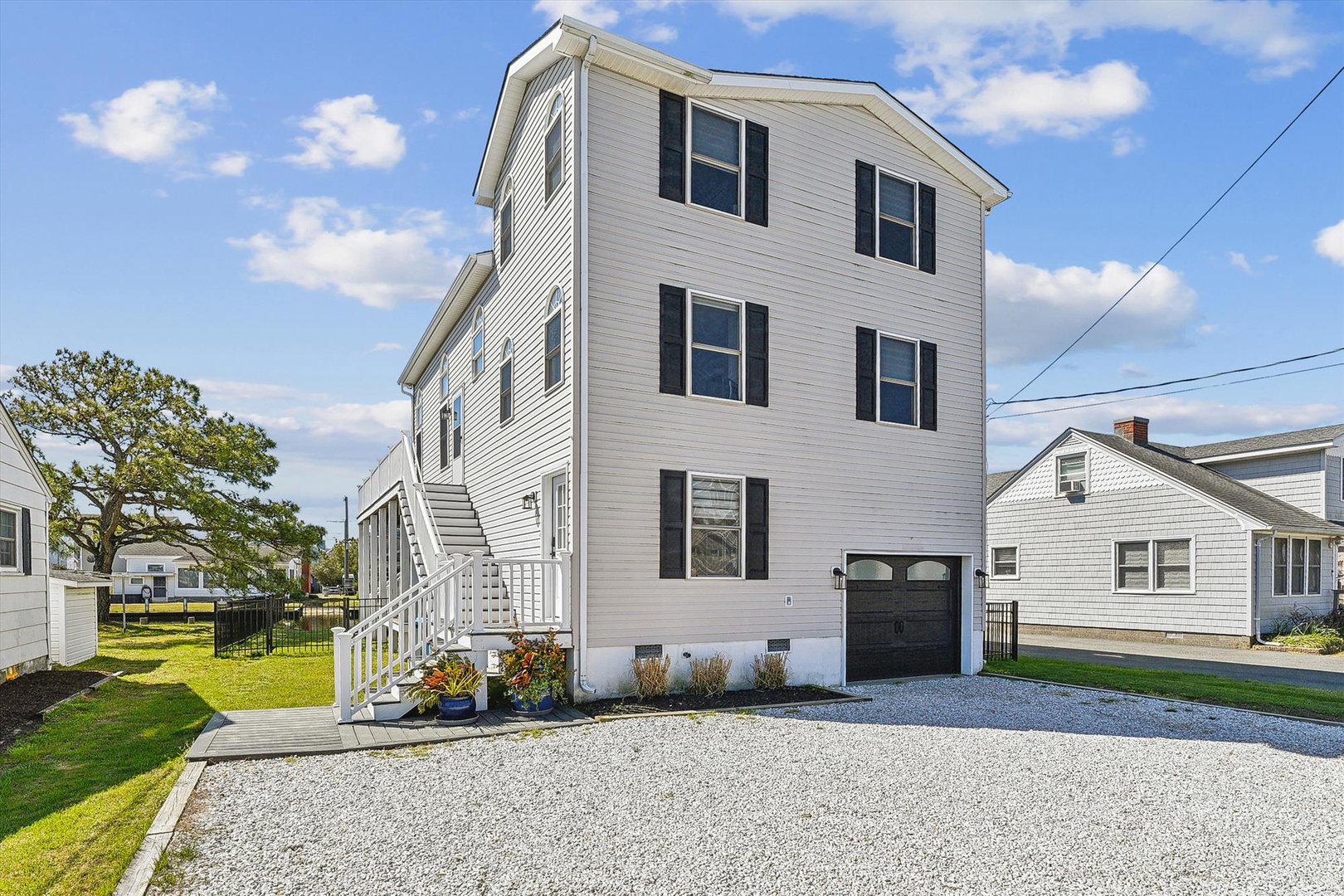 A well-maintained three-story coastal property with private parking and garage, set in a friendly residential neighborhood under sunny skies.