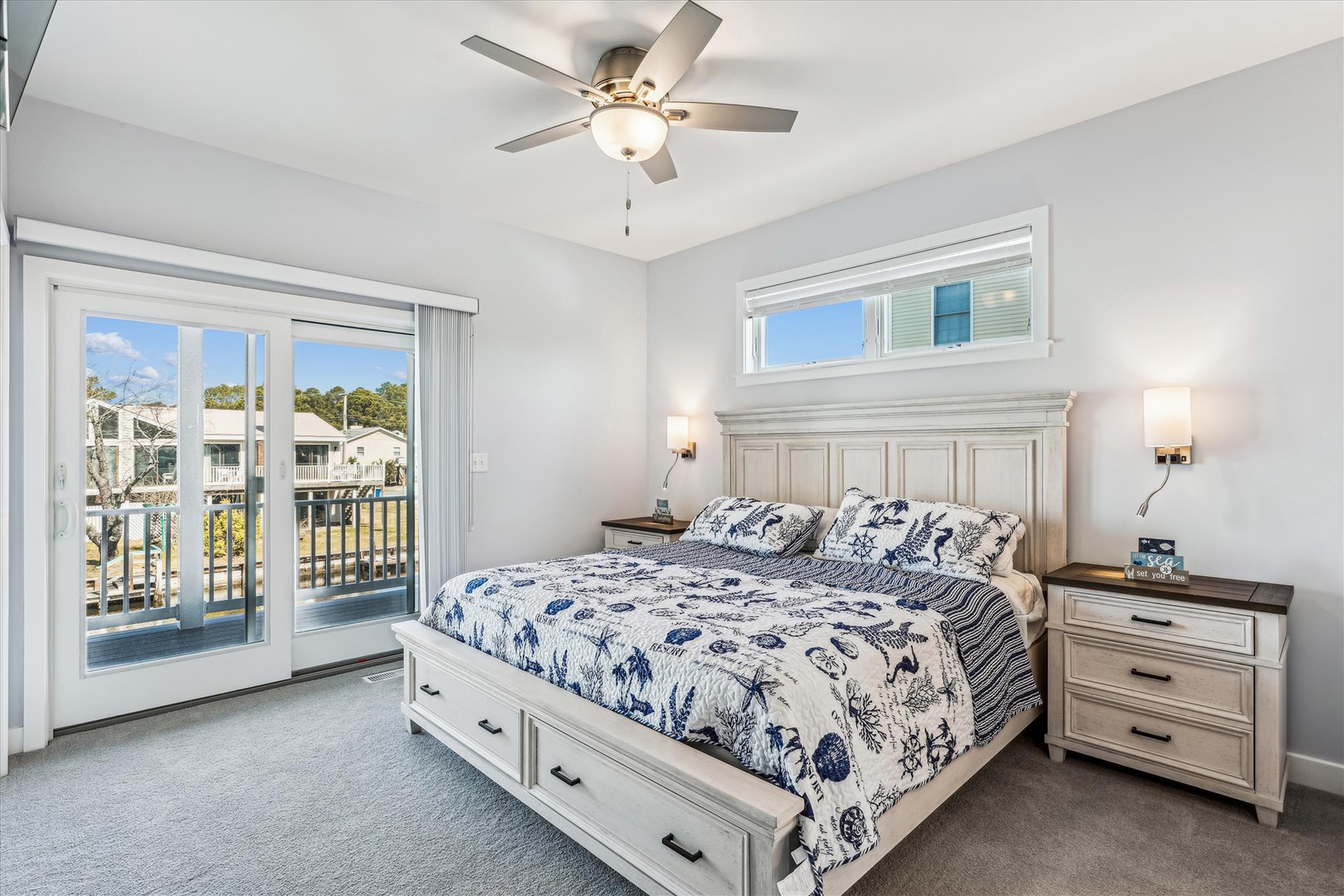 Your bright coastal bedroom features a plush king bed with storage drawers, ceiling fan for comfort, and balcony access to enjoy fresh air and neighborhood views.