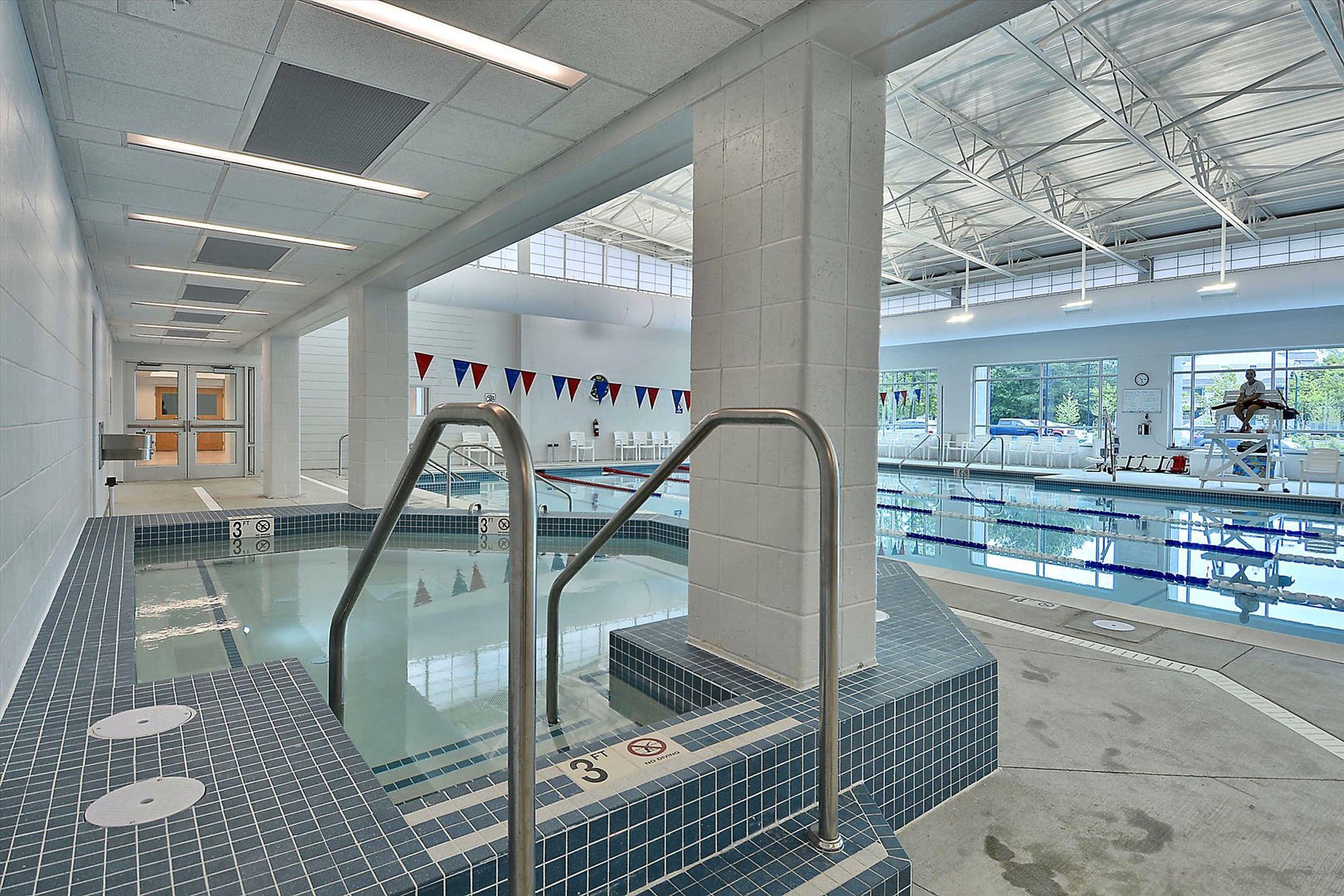 Modern aquatic center with pools, hot tub, and competitive swimming lanes under soaring glass ceilings.