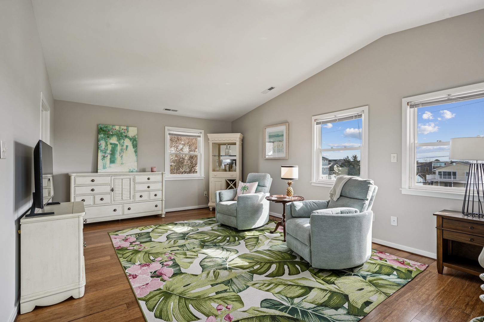 Relax in your bright living space with plush chairs and coastal charm, where warm wood floors meet ocean breezes through sun-filled windows.